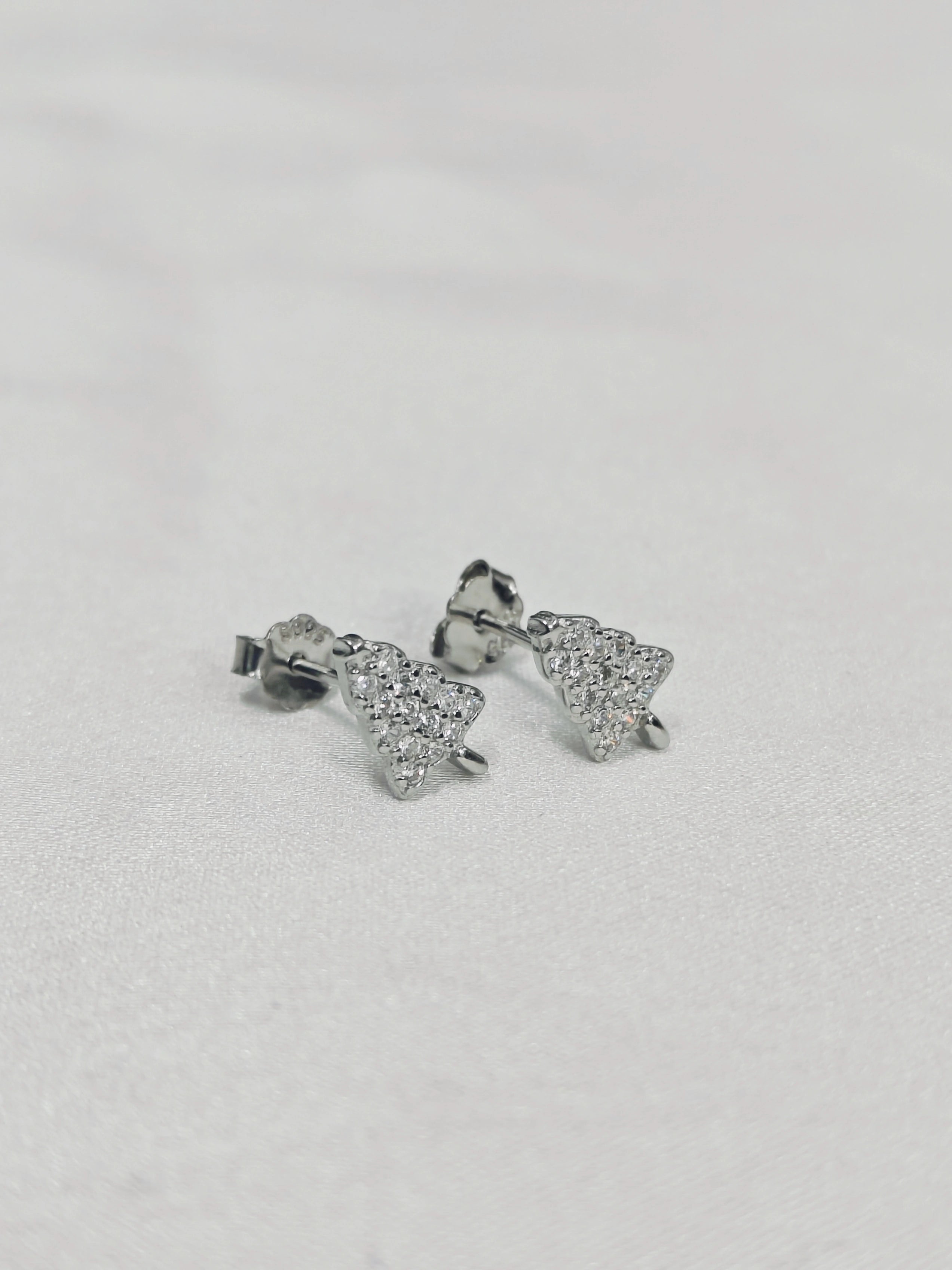 Pair of silver star-shaped earrings on a light gray background