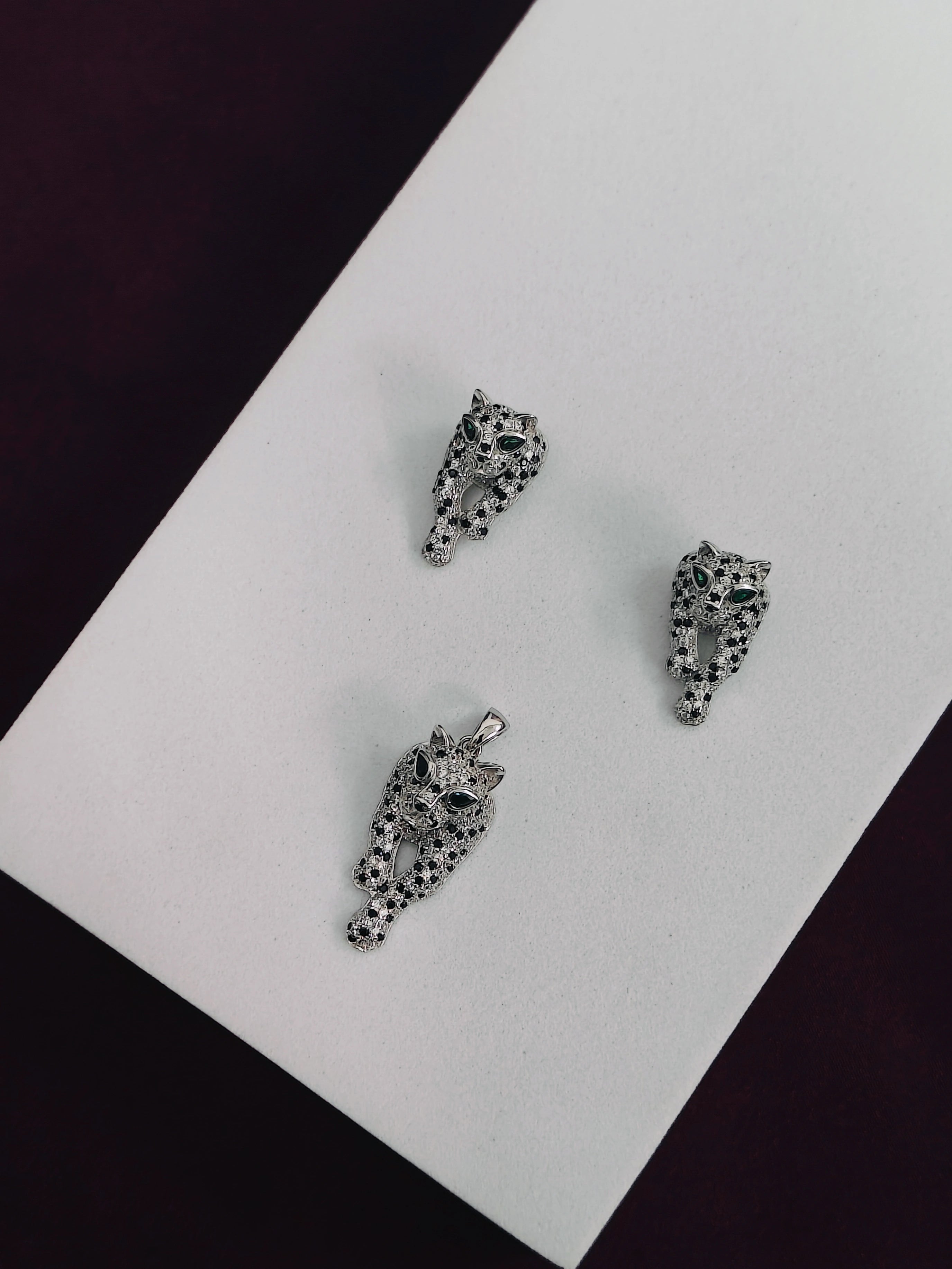 Two silver animal-shaped pendants on a white card with a black background