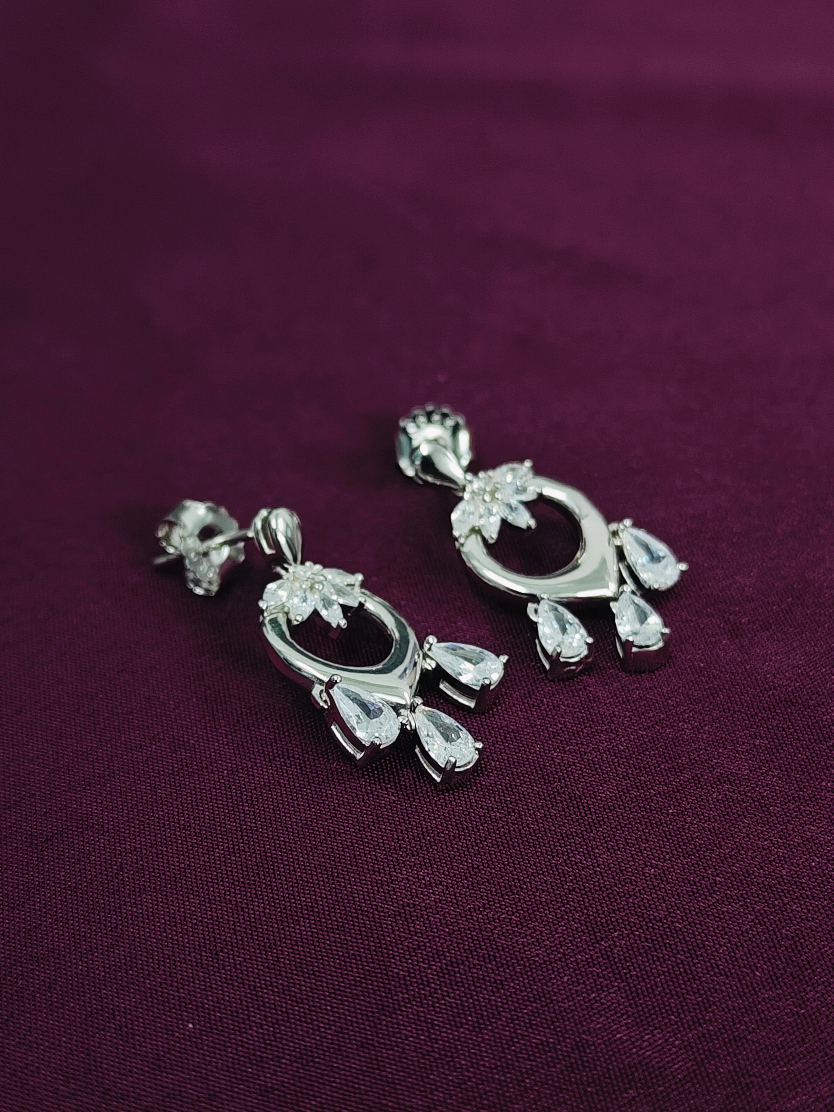 Pair of silver earrings on a purple fabric background