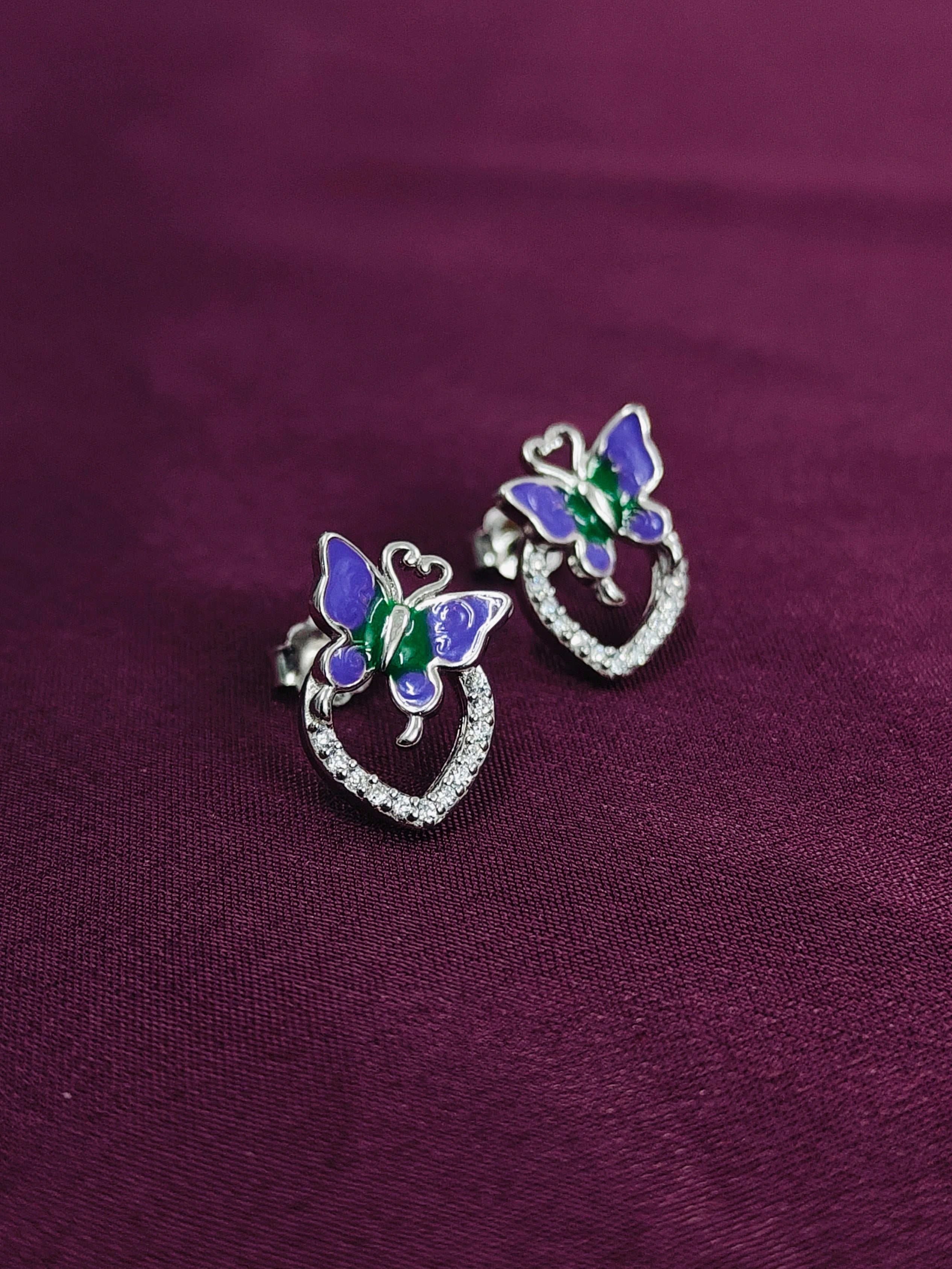 Butterfly earrings on a purple fabric background