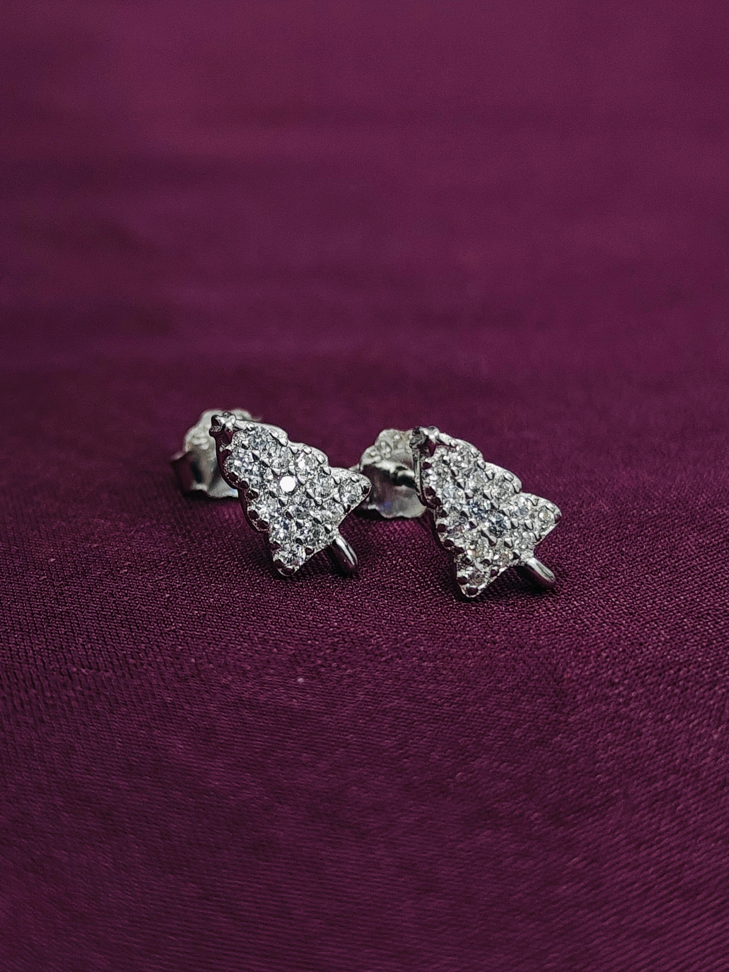 Silver tree-shaped earrings on a purple fabric background