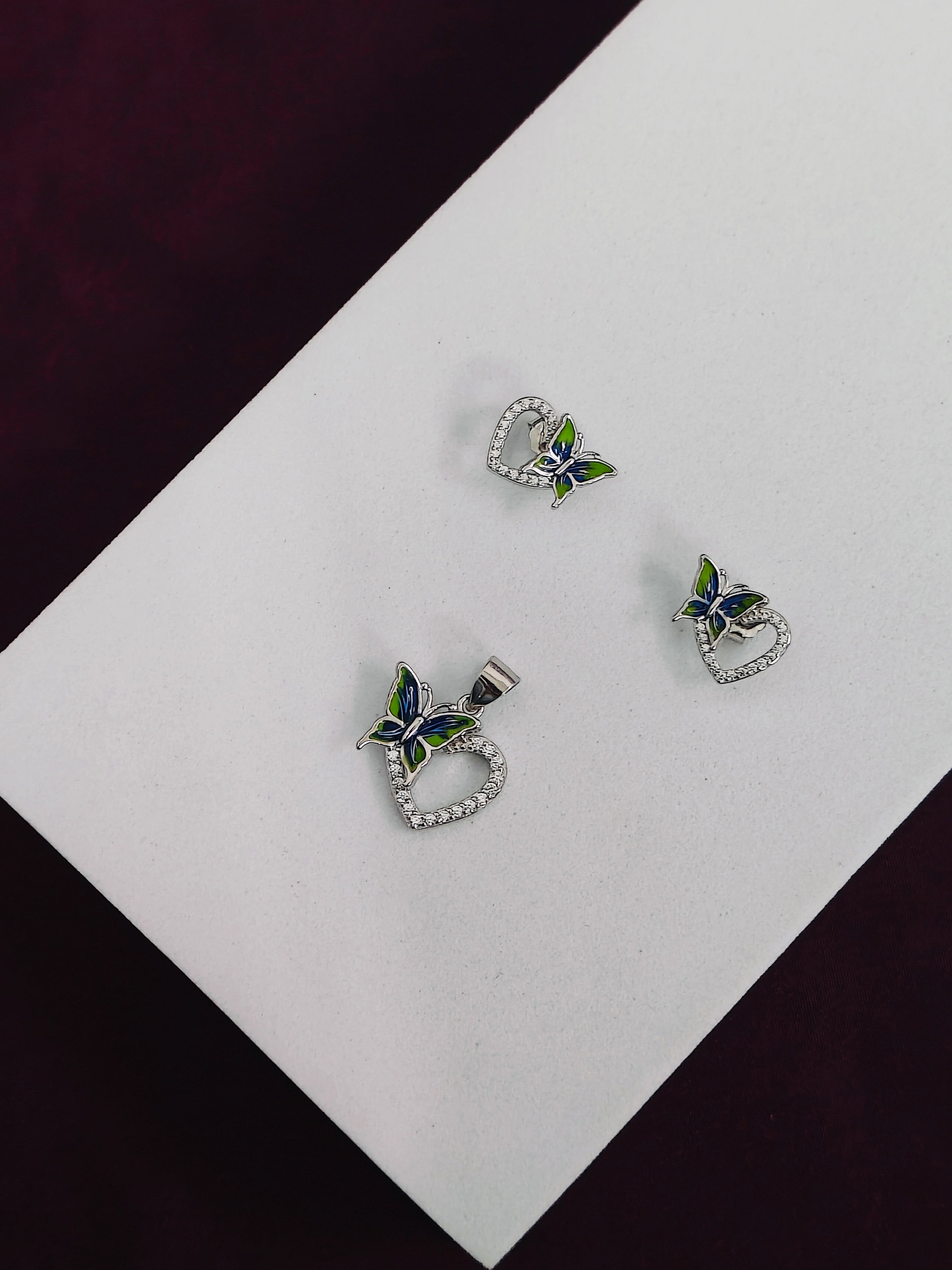 Butterfly heart earrings on a white card with a black background