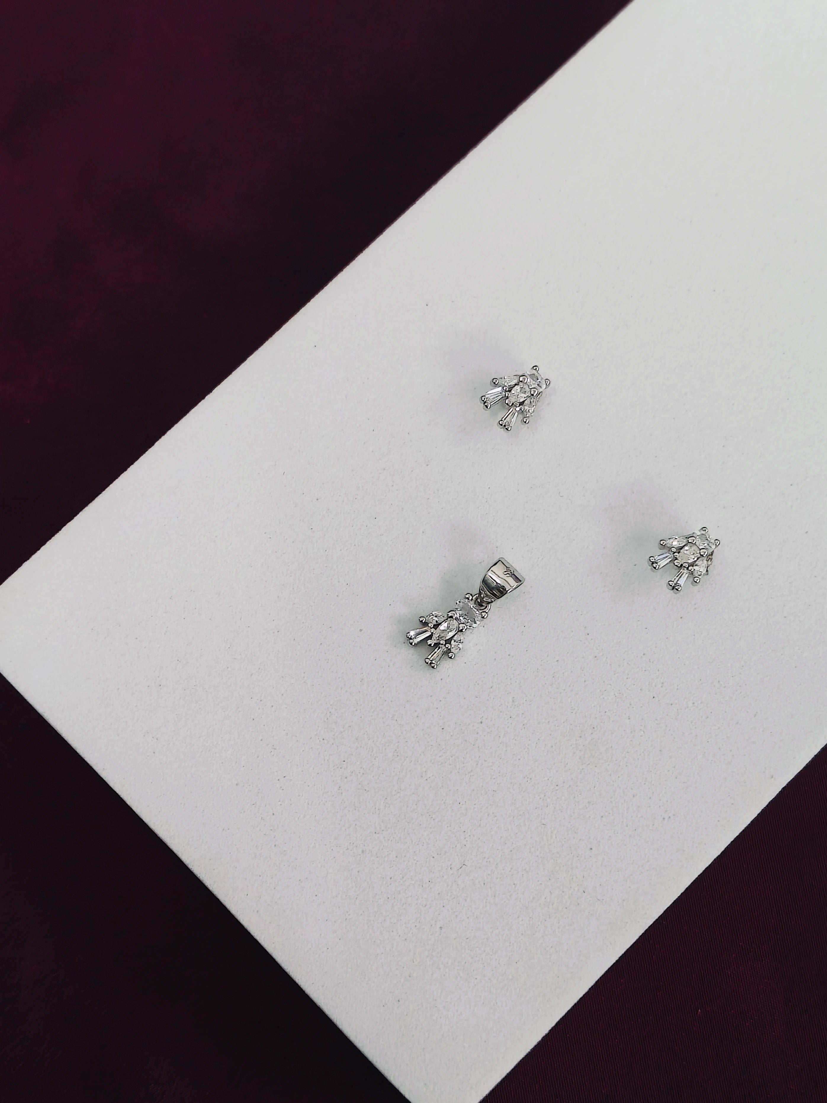 Silver earrings on a white card with a dark background