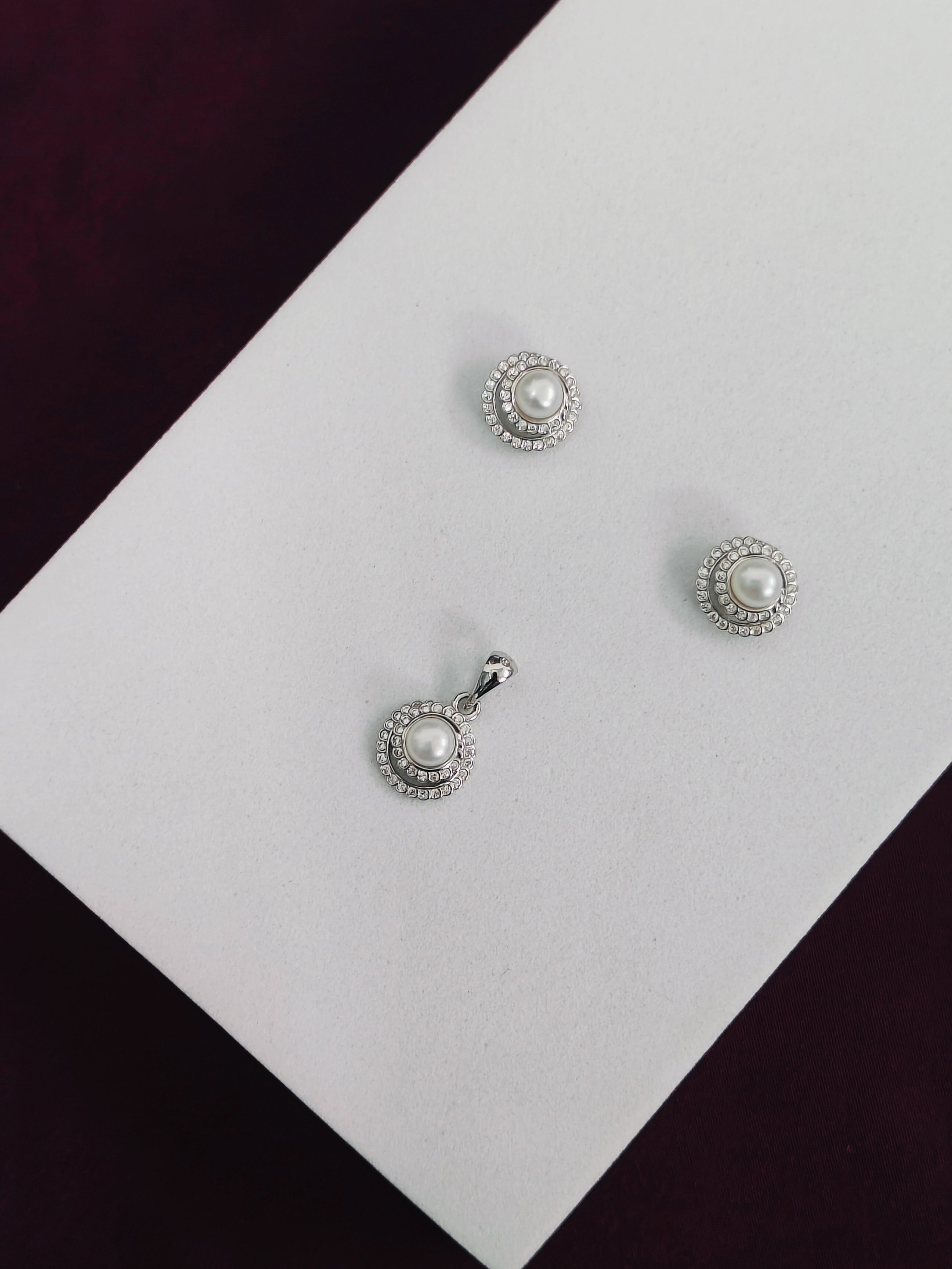 Silver earrings with pearl-like stones on a white card