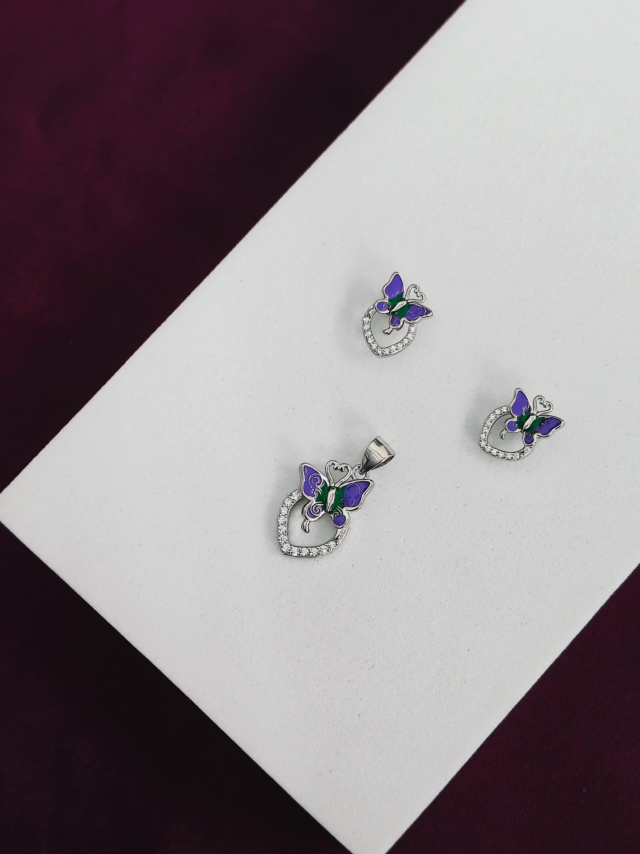 Butterfly-themed jewelry set on a white and purple fabric background