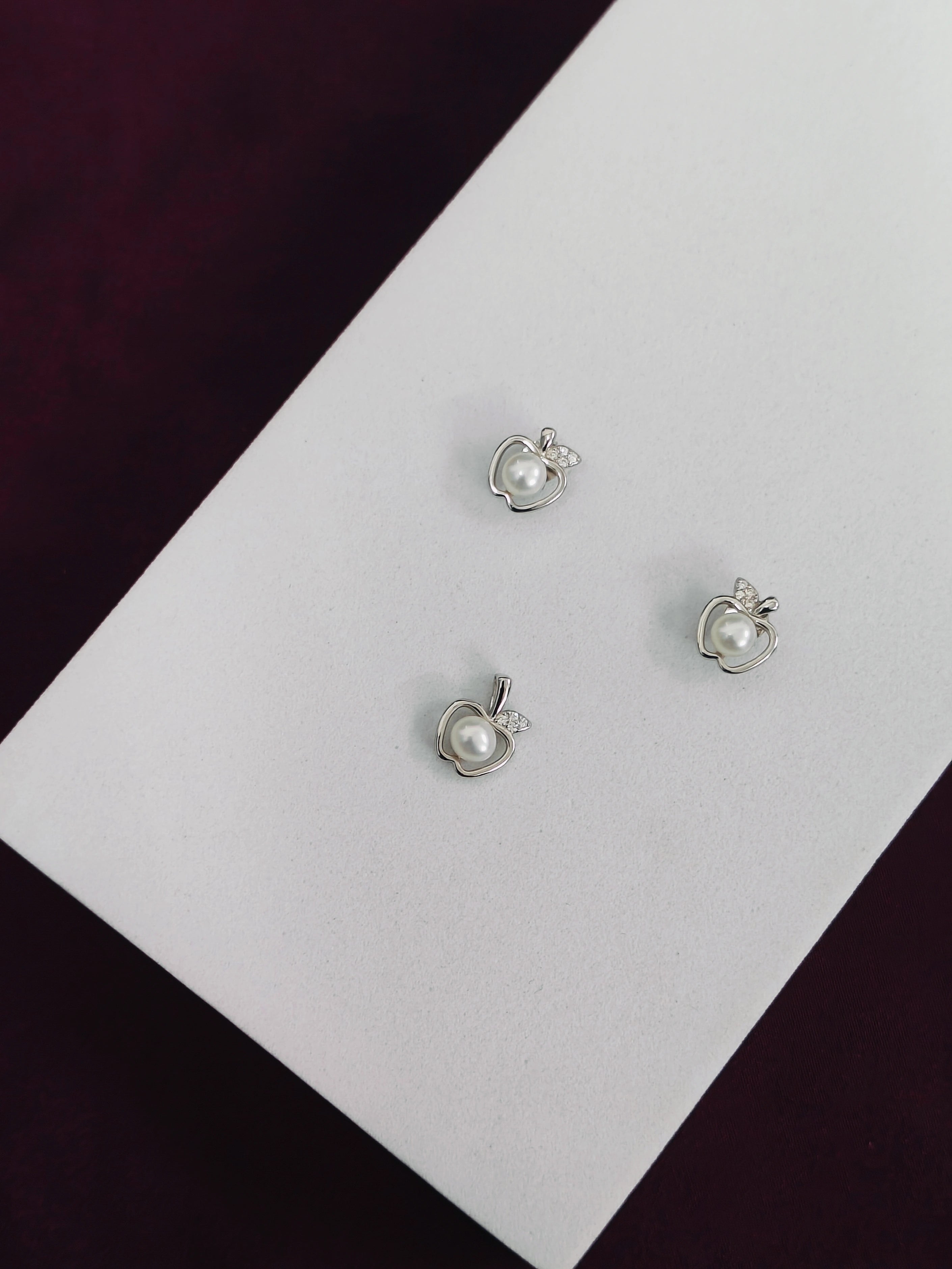 Three pearl earrings on a white card with a dark background