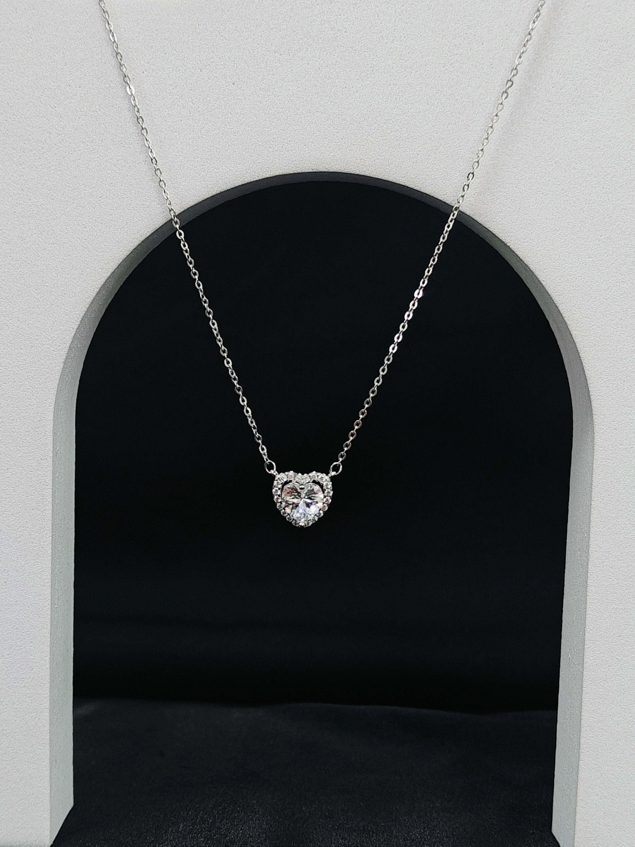 Heart-shaped diamond necklace on a black background with a white archway