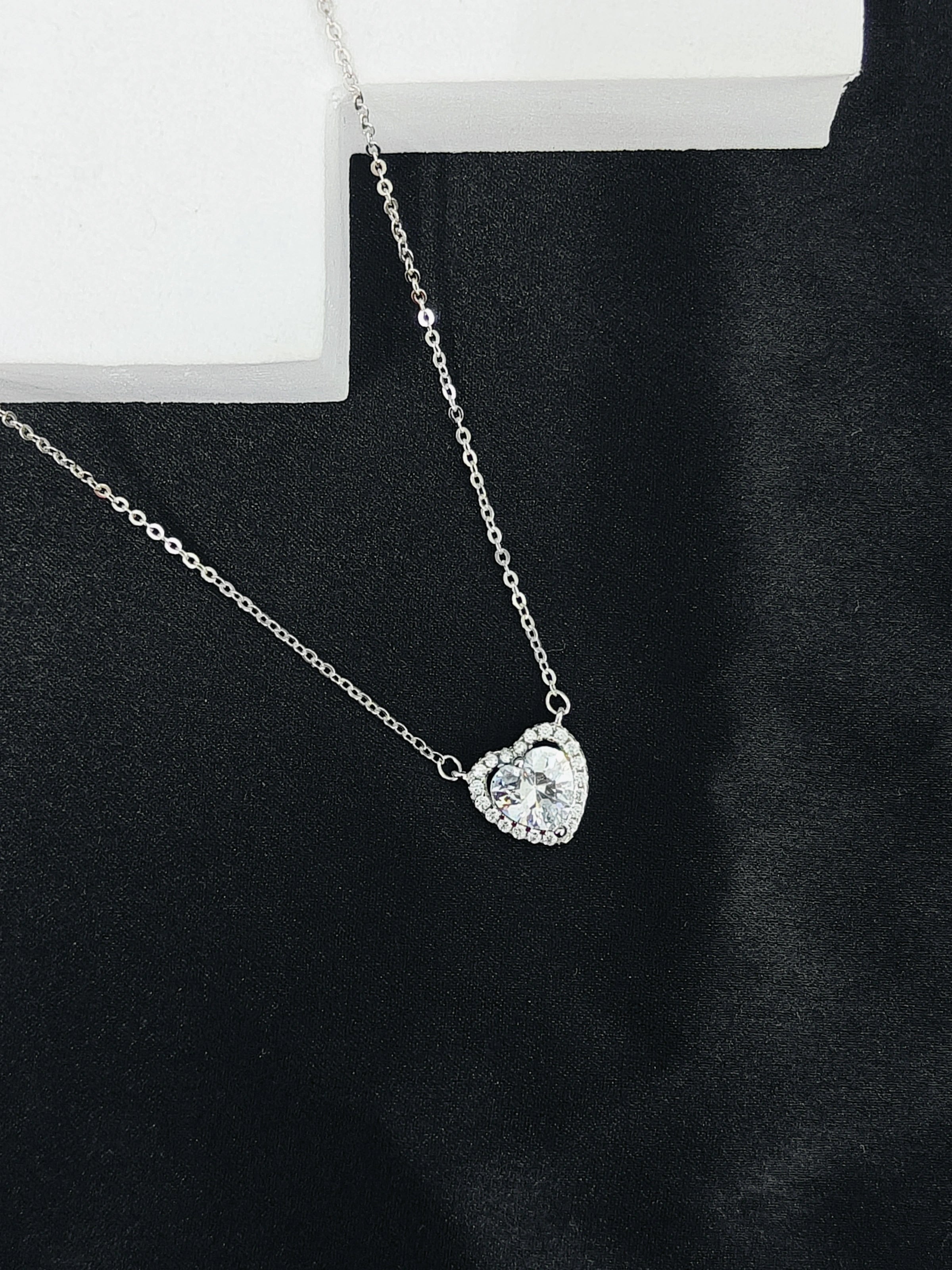 Silver necklace with a heart-shaped pendant on a black background