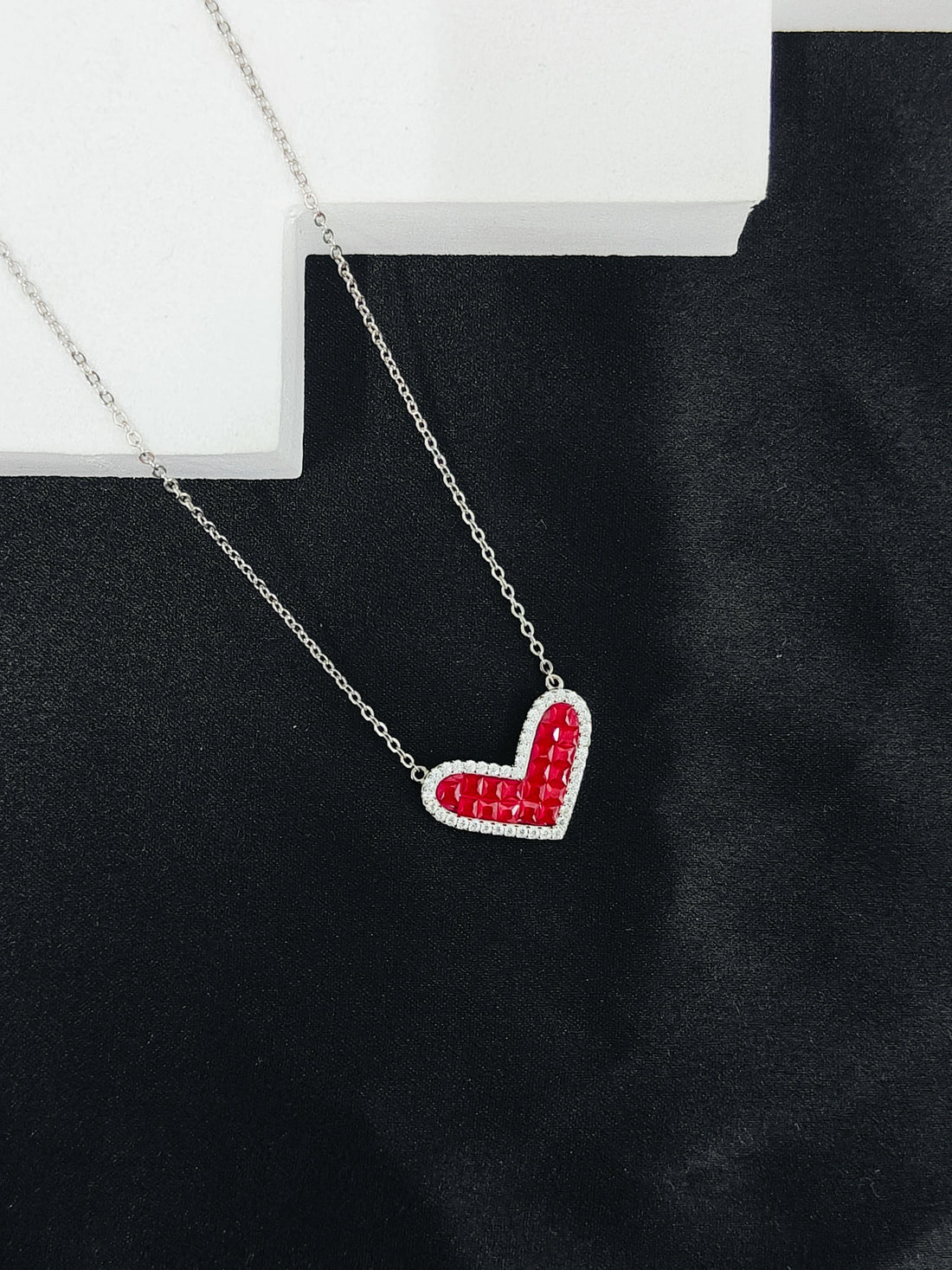 Necklace with a red heart-shaped pendant on a black background