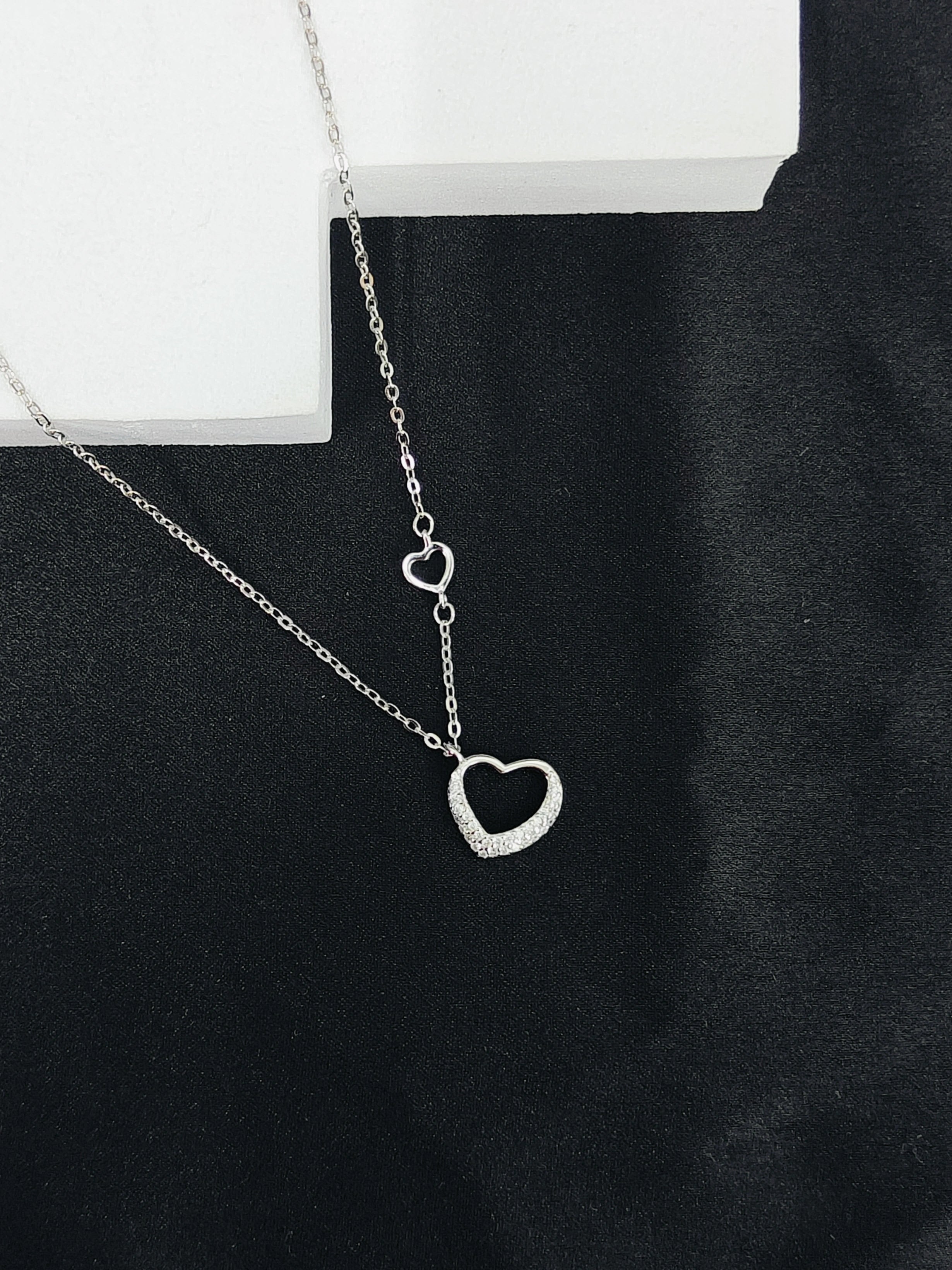 Silver necklace with a heart pendant on a black background