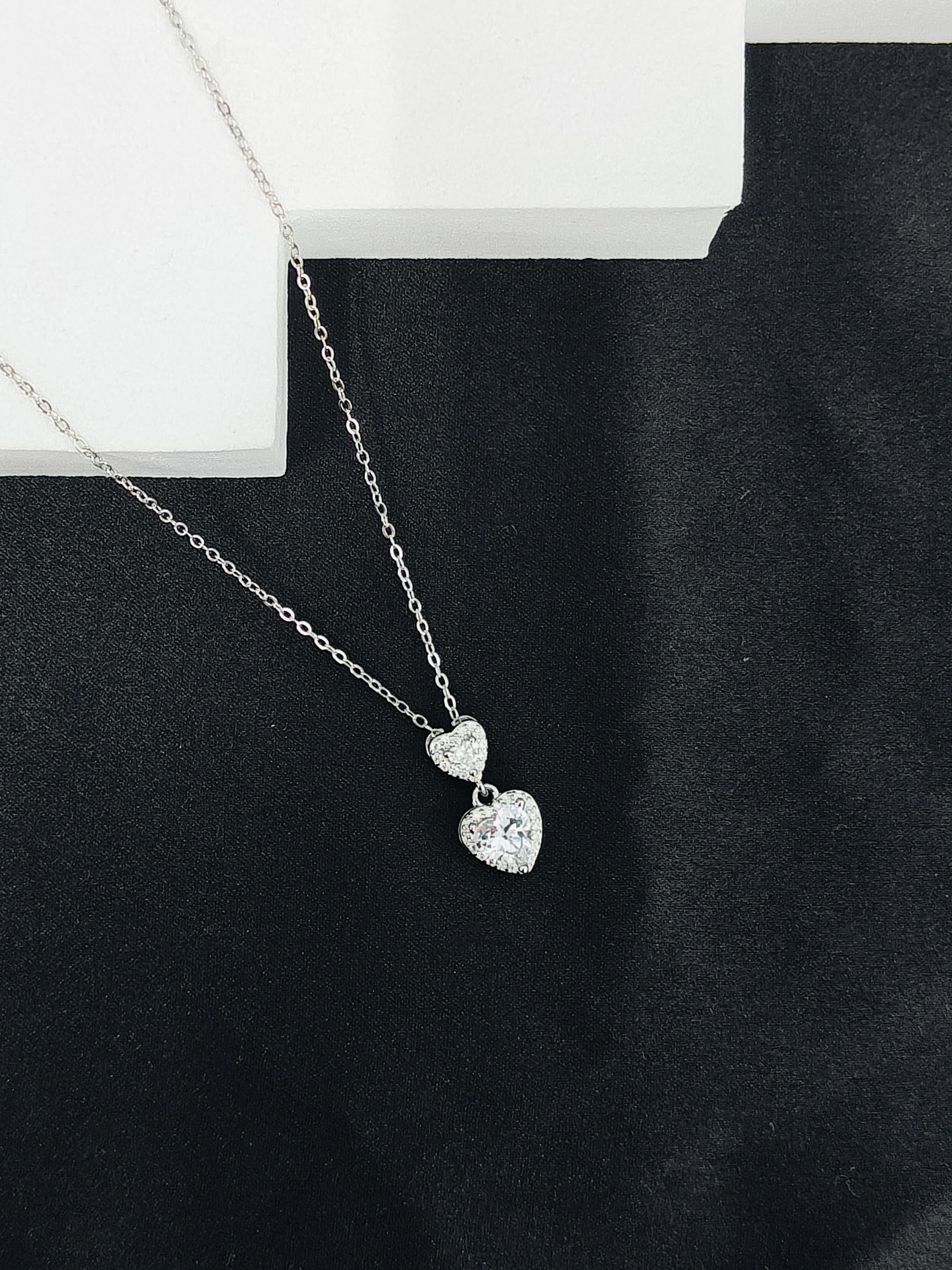 Silver necklace with heart-shaped pendants on a black surface