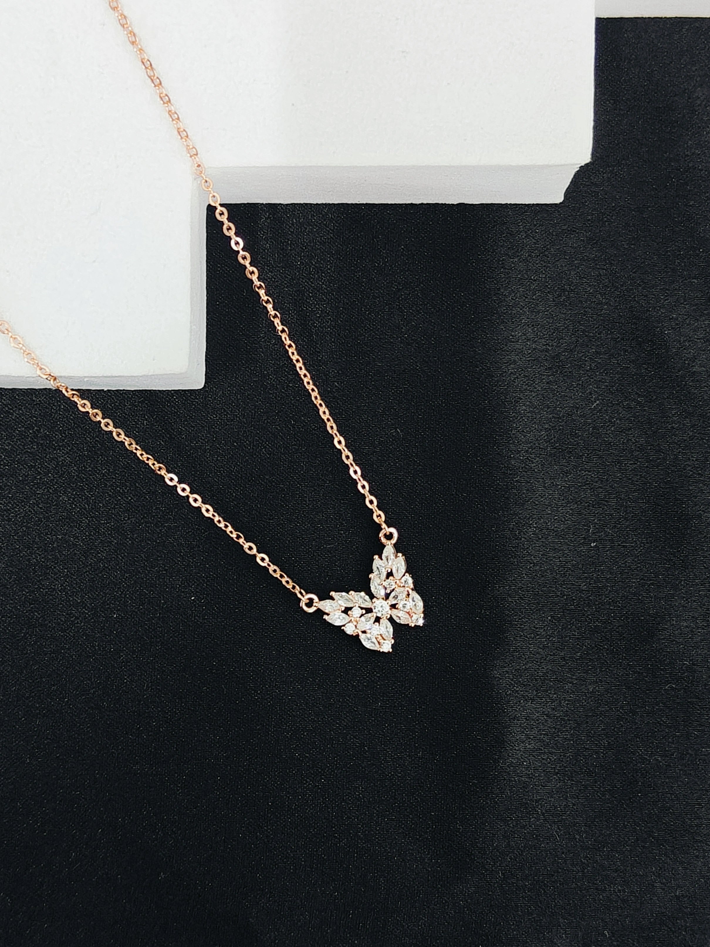 Rose gold necklace with a butterfly pendant on a black background
