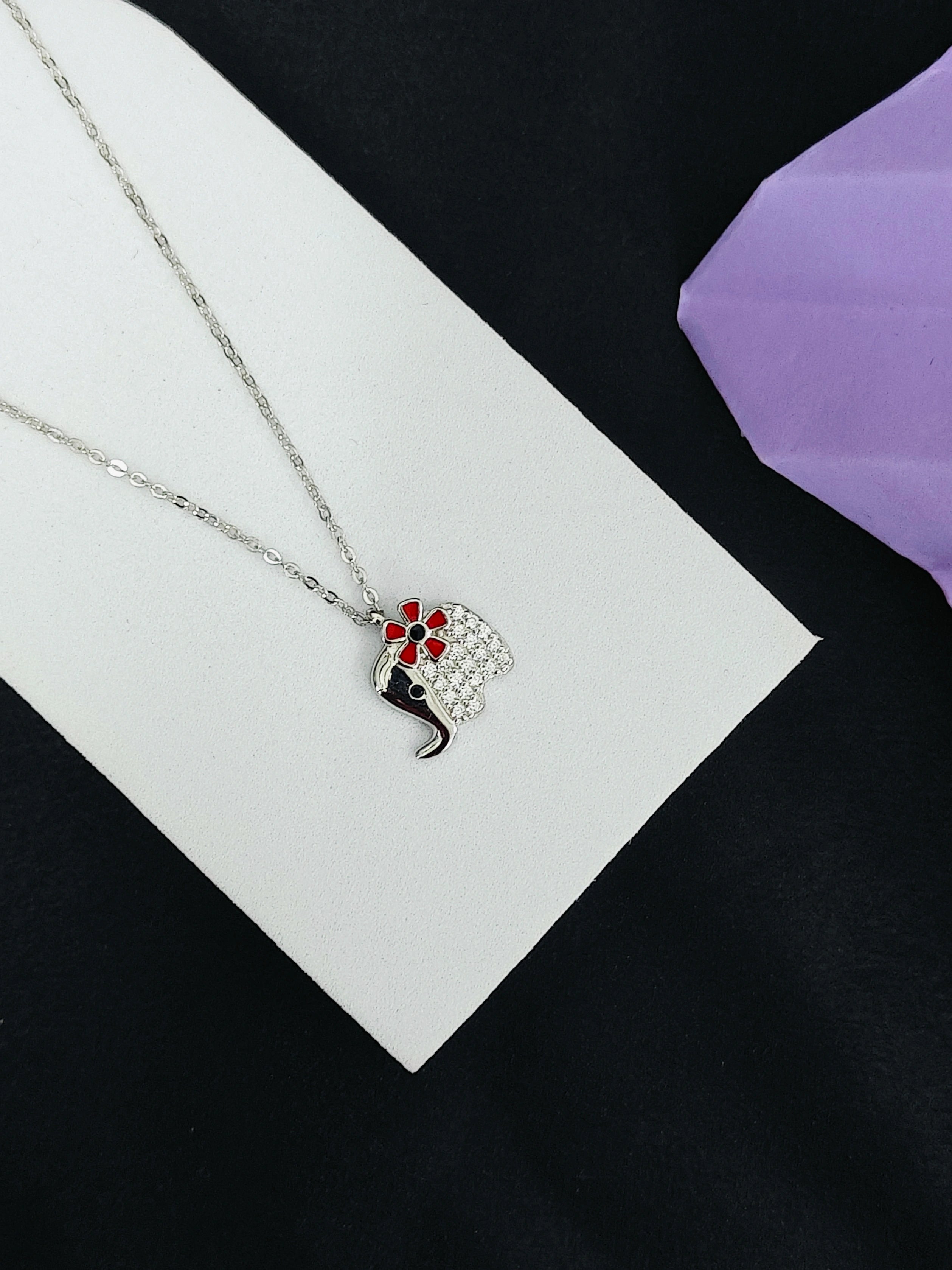 Necklace with a decorative pendant on a white card against a black background