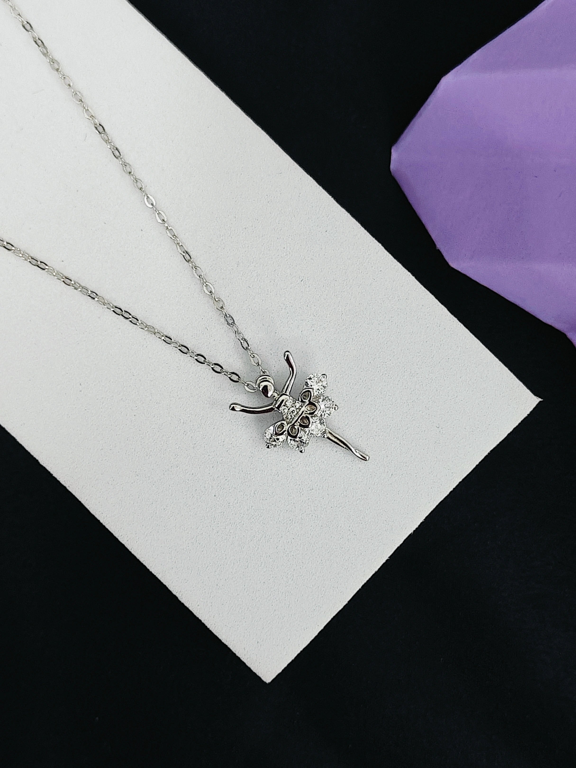 Silver necklace with a star-shaped pendant on a white card with a purple fabric background