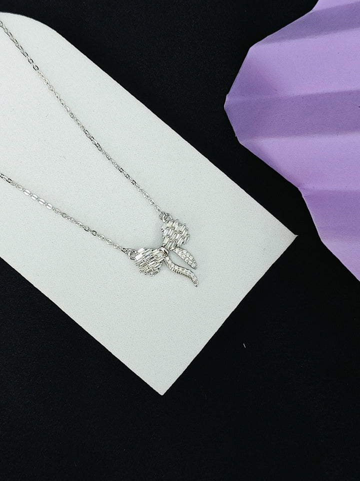 Silver necklace with a butterfly pendant on a white card against a black background