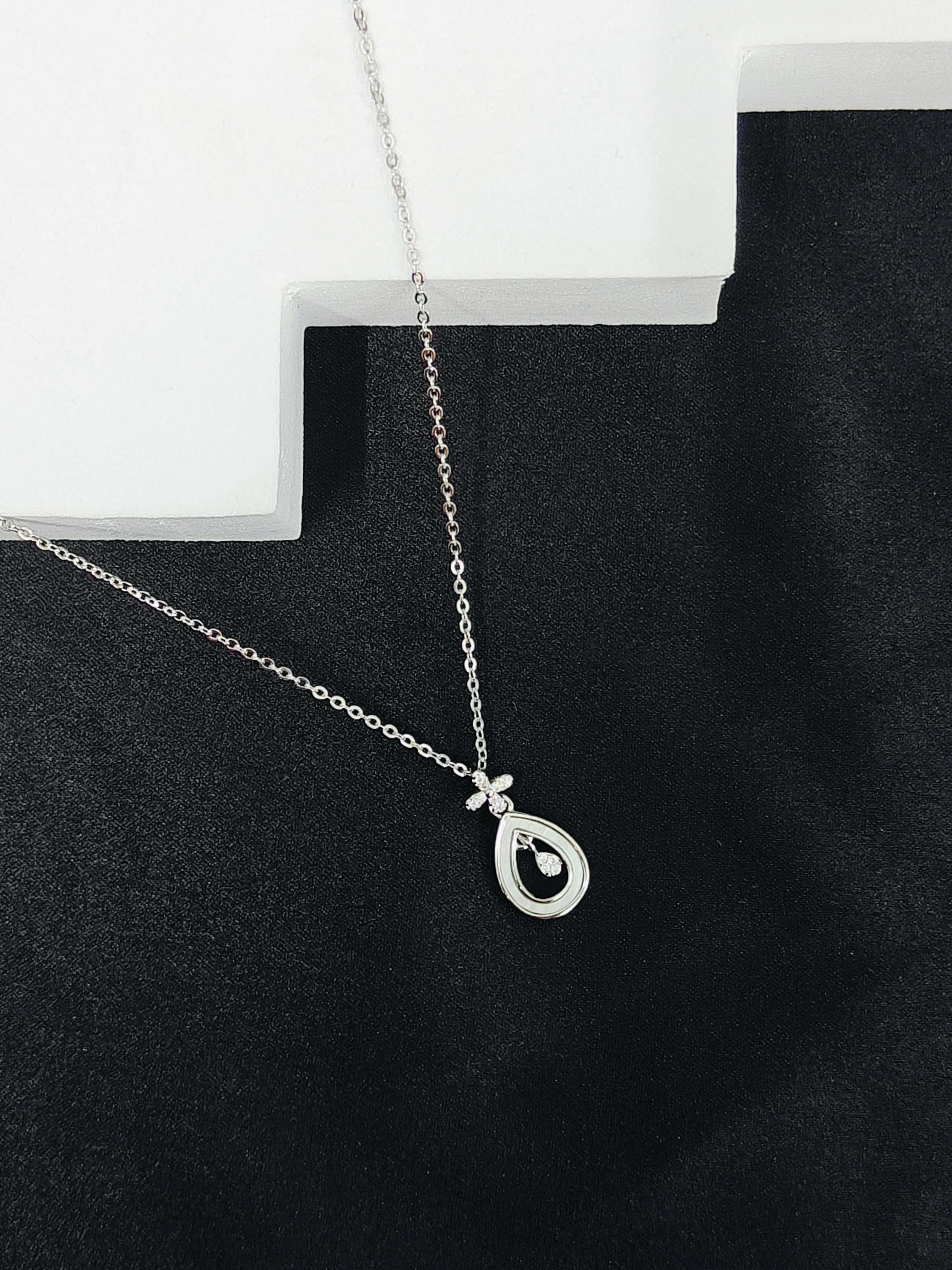 Silver necklace with a teardrop pendant on a black surface