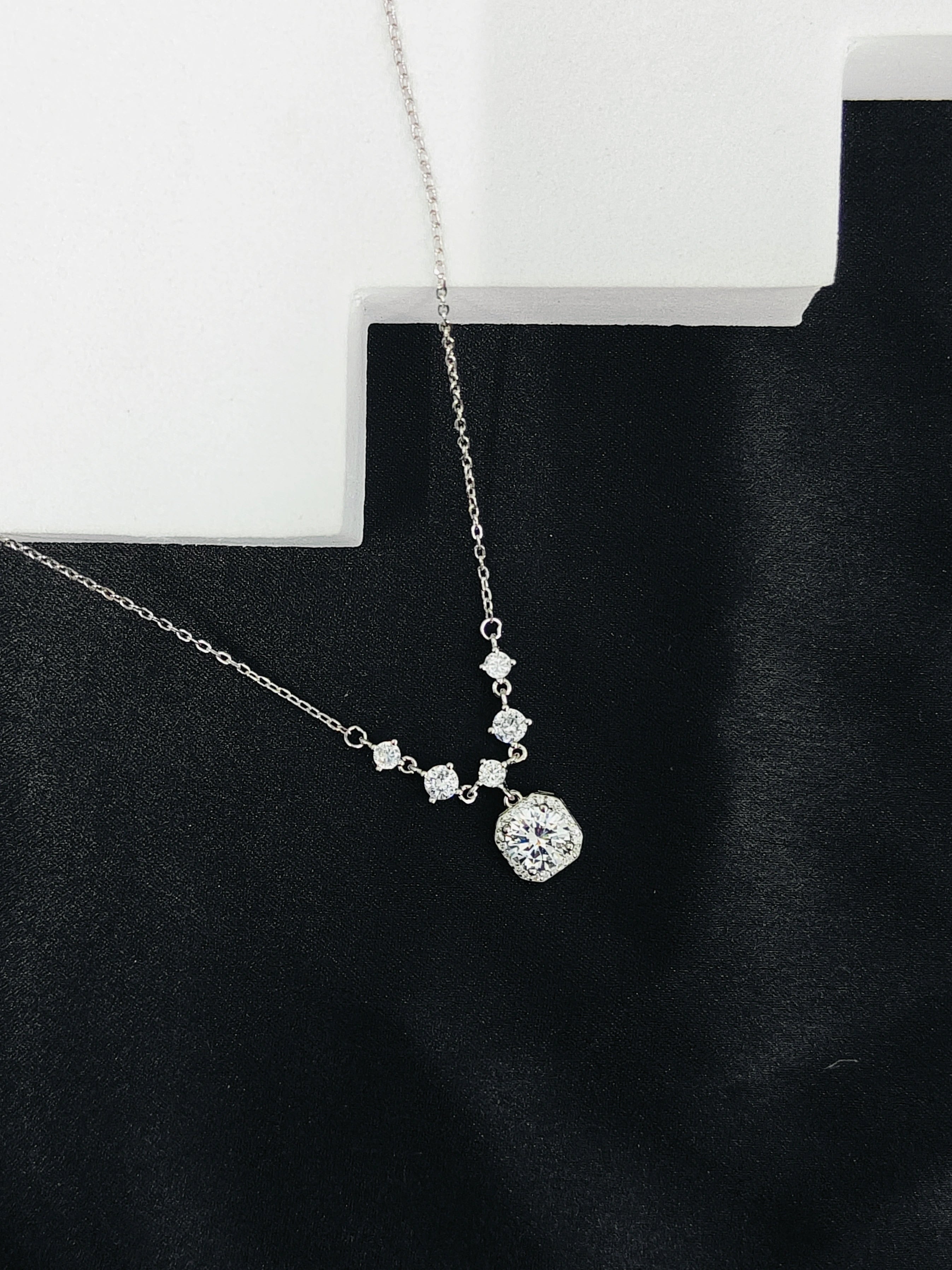 Silver necklace with diamond pendants on a black background
