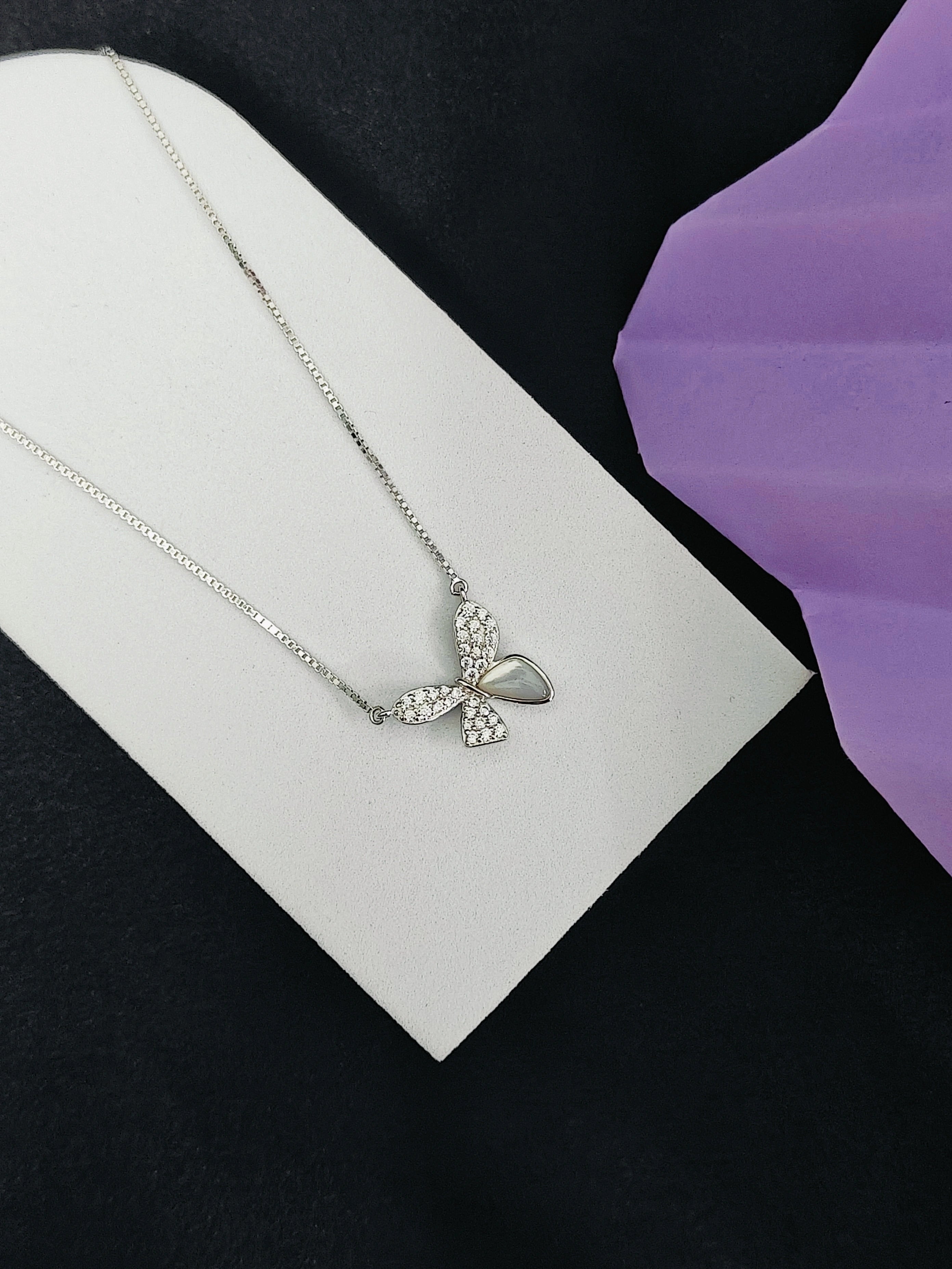 Butterfly necklace on a white card with a purple background