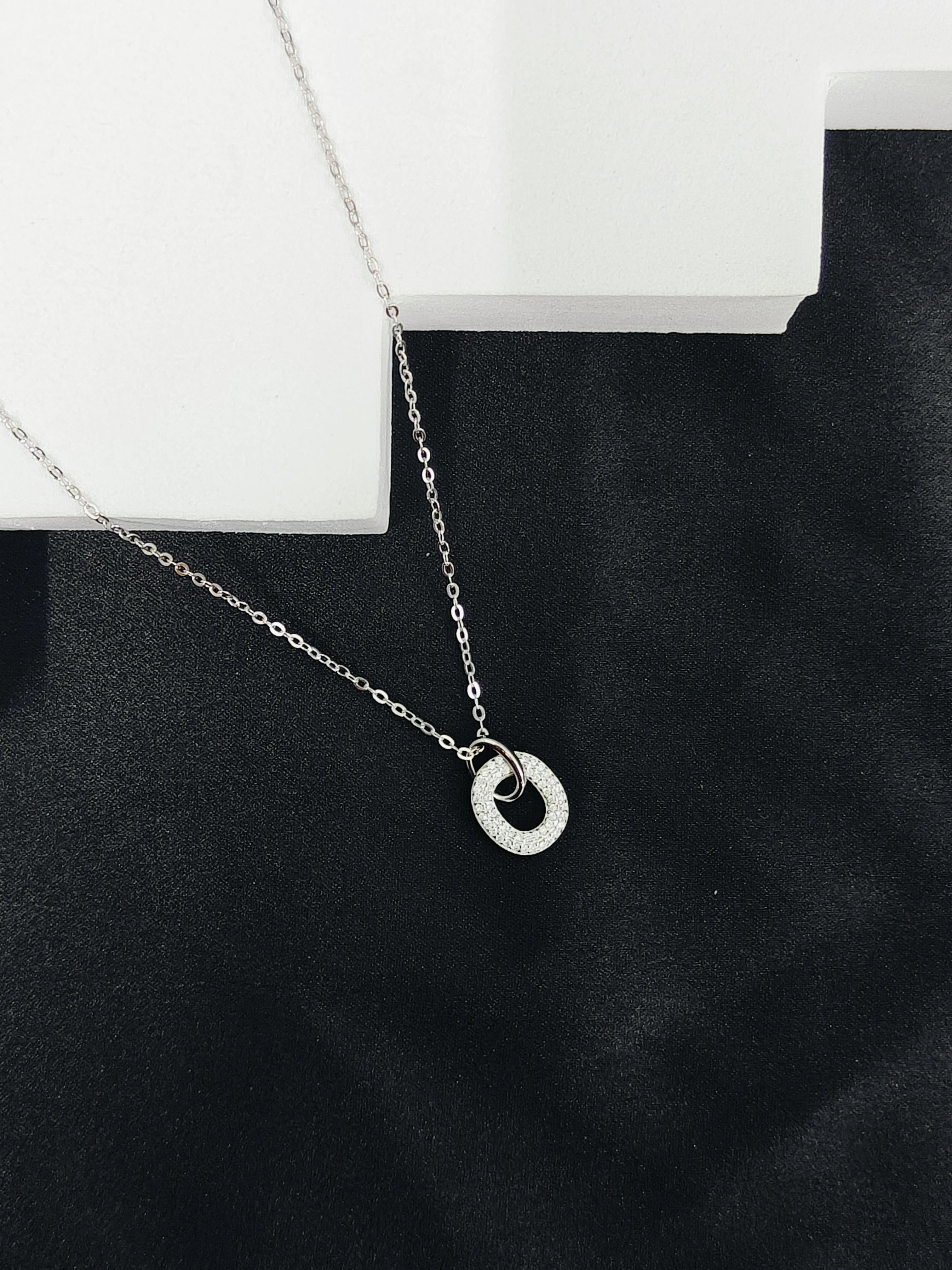 Silver necklace with a circular pendant on a black surface