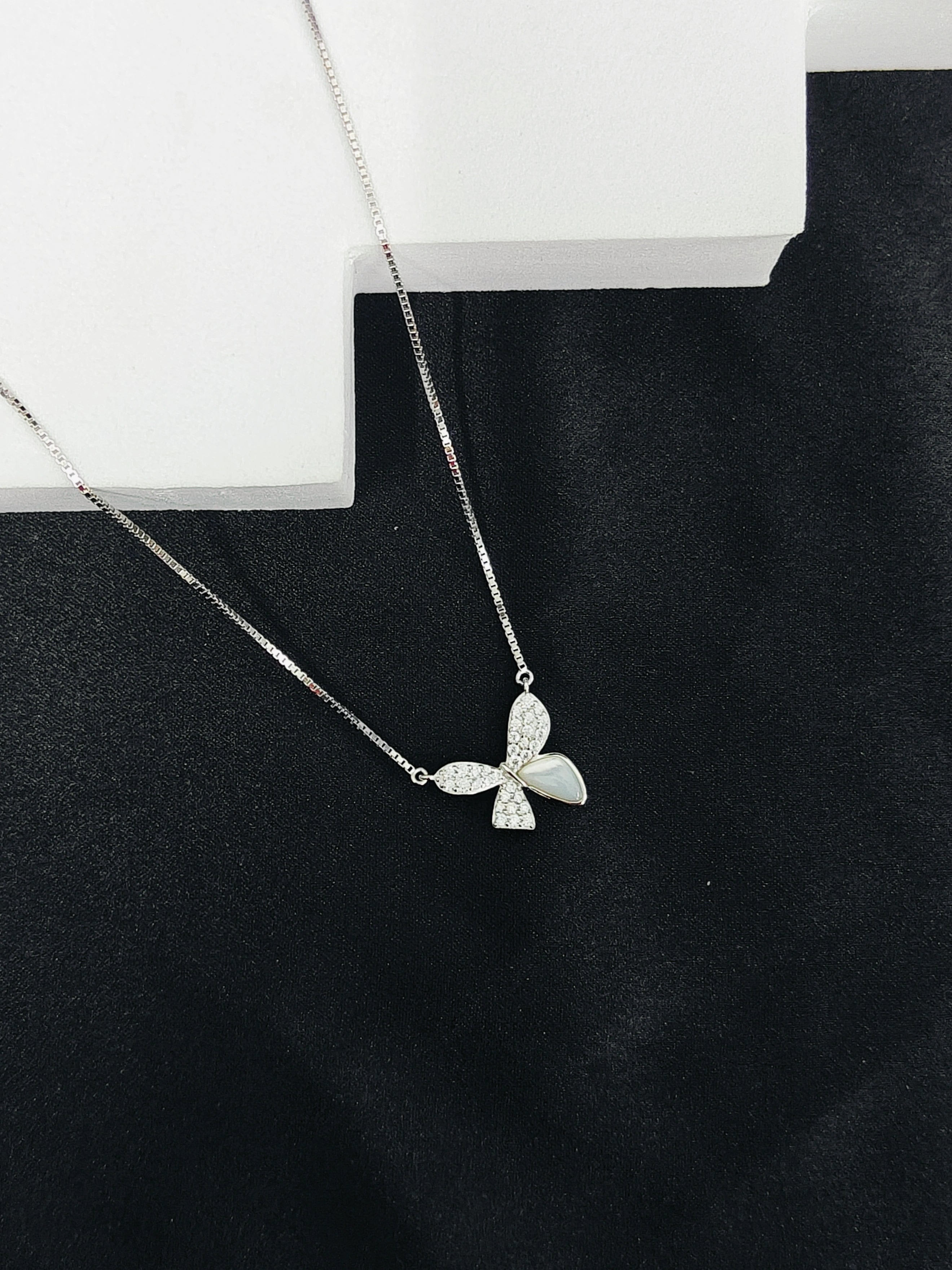 Silver butterfly necklace on a black background