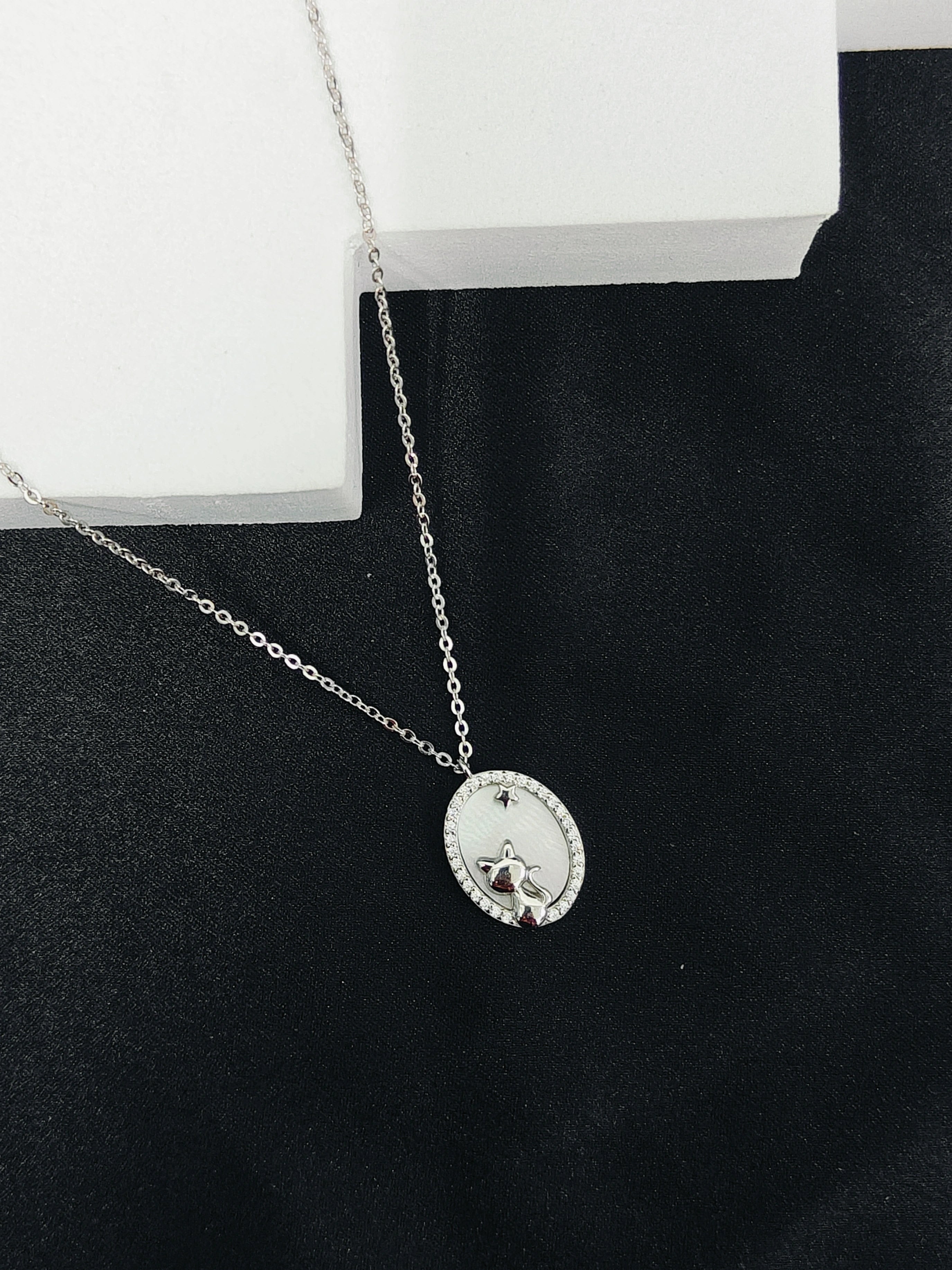 Silver necklace with a round pendant on a black surface