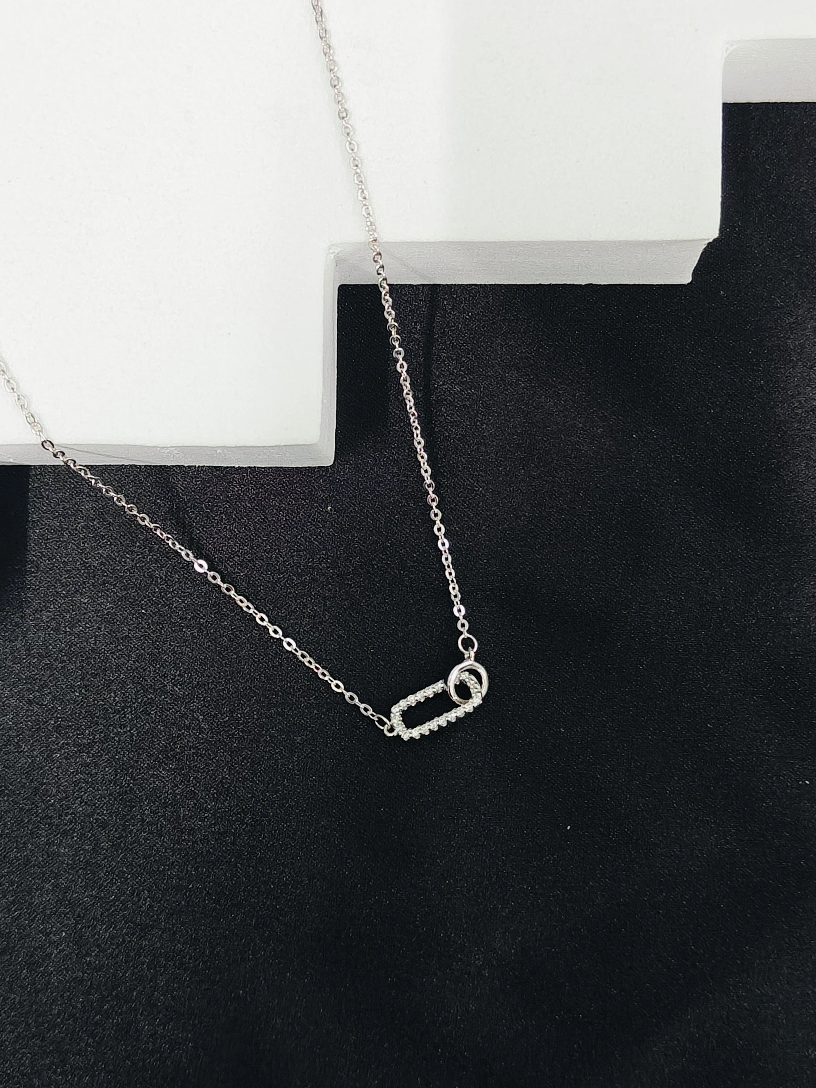 Silver necklace with a small pendant on a black surface