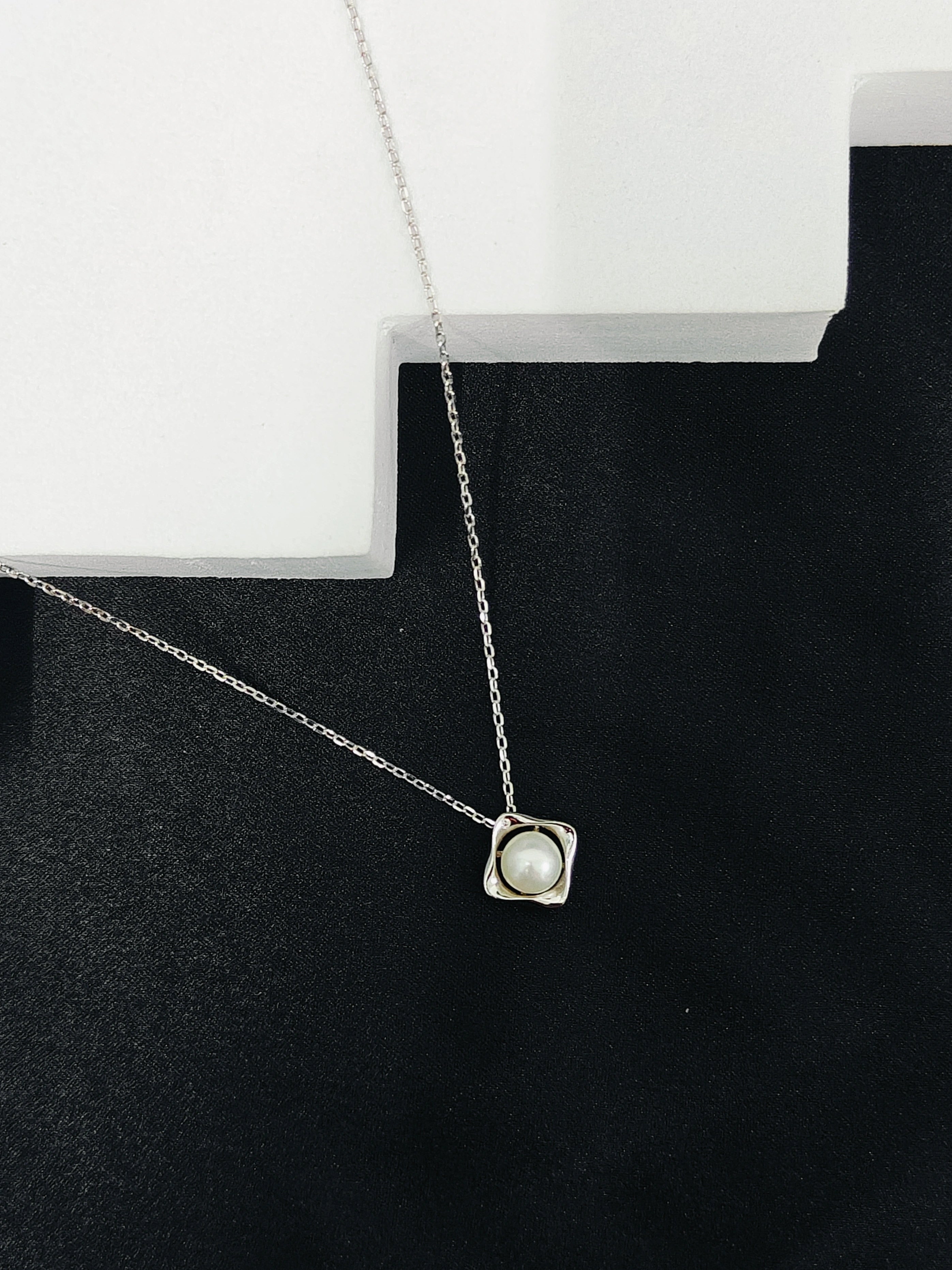 Necklace with a pendant on a black stand against a white background