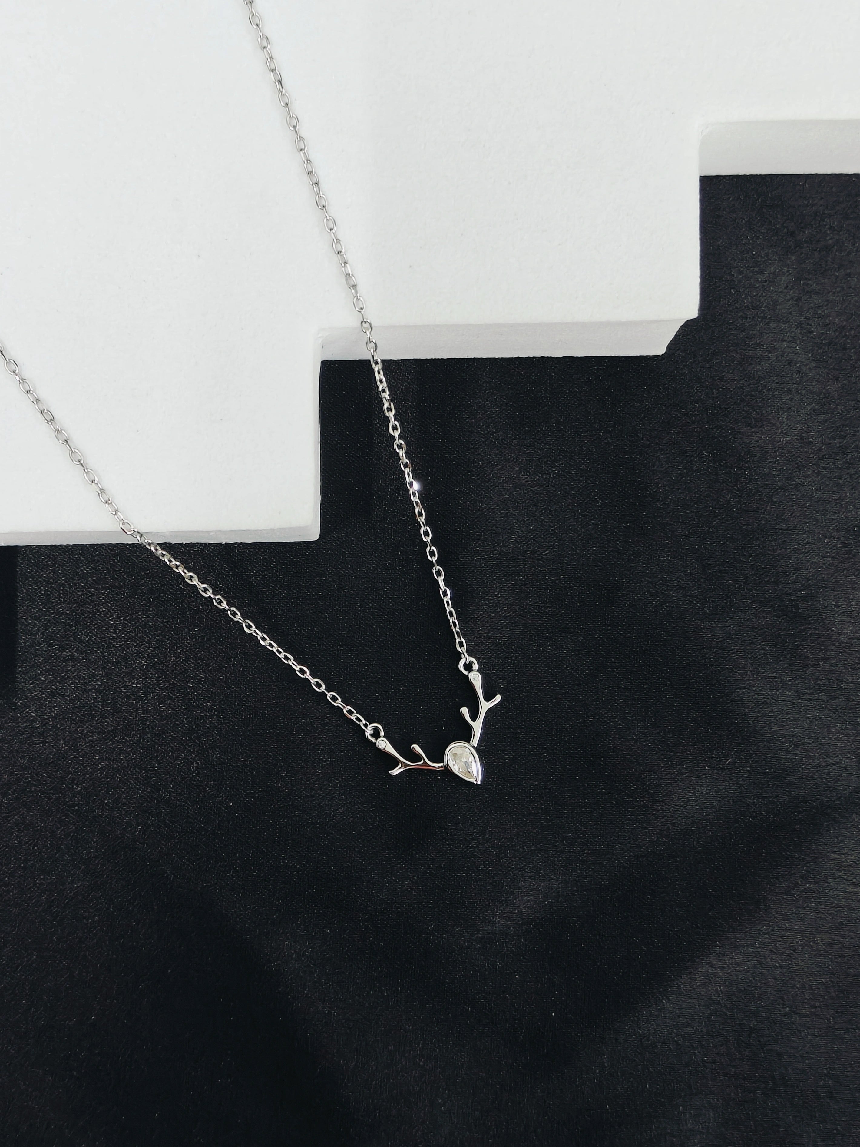 Silver necklace with a delicate pendant on a black surface