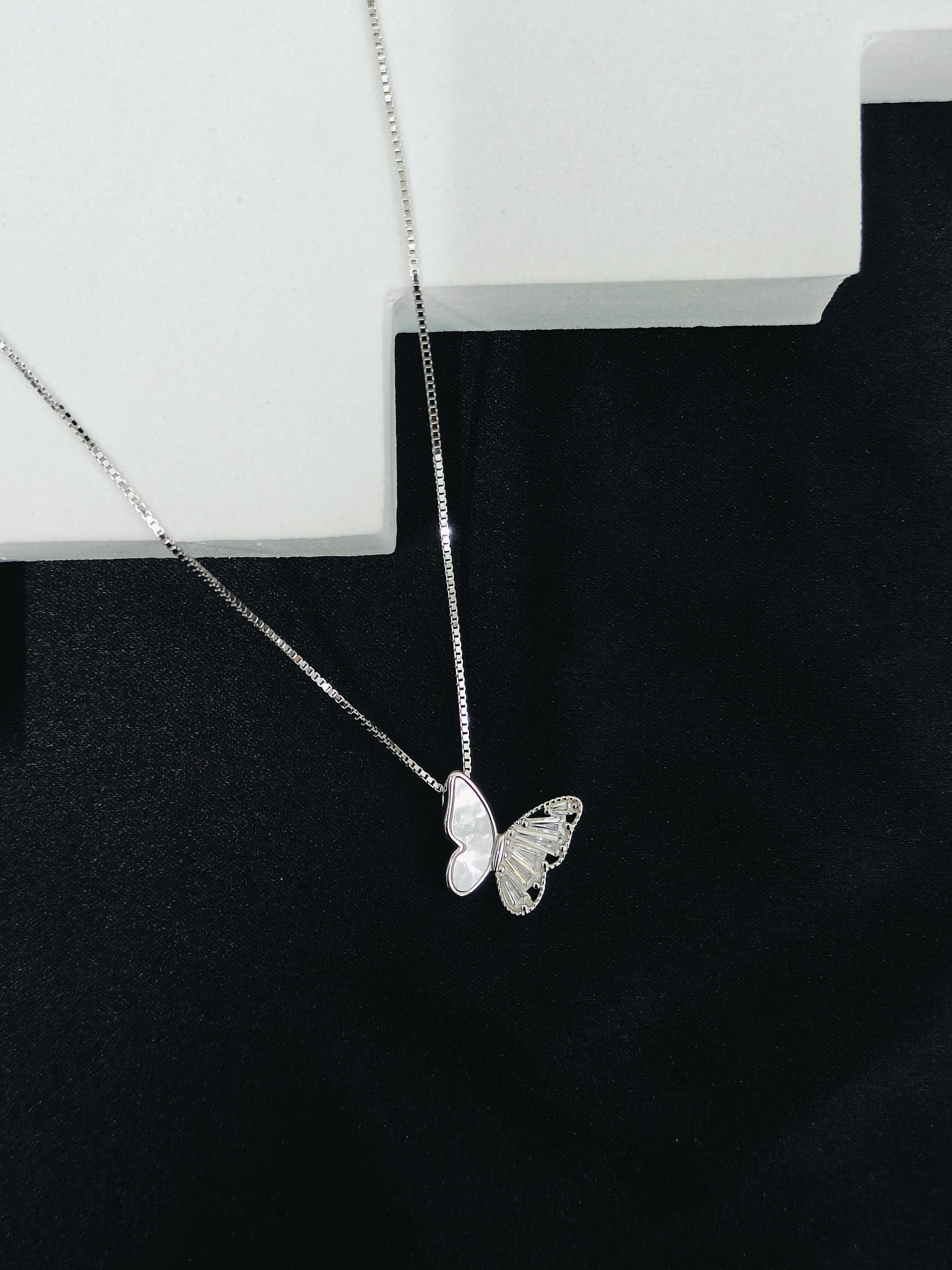 Silver butterfly necklace on a black background