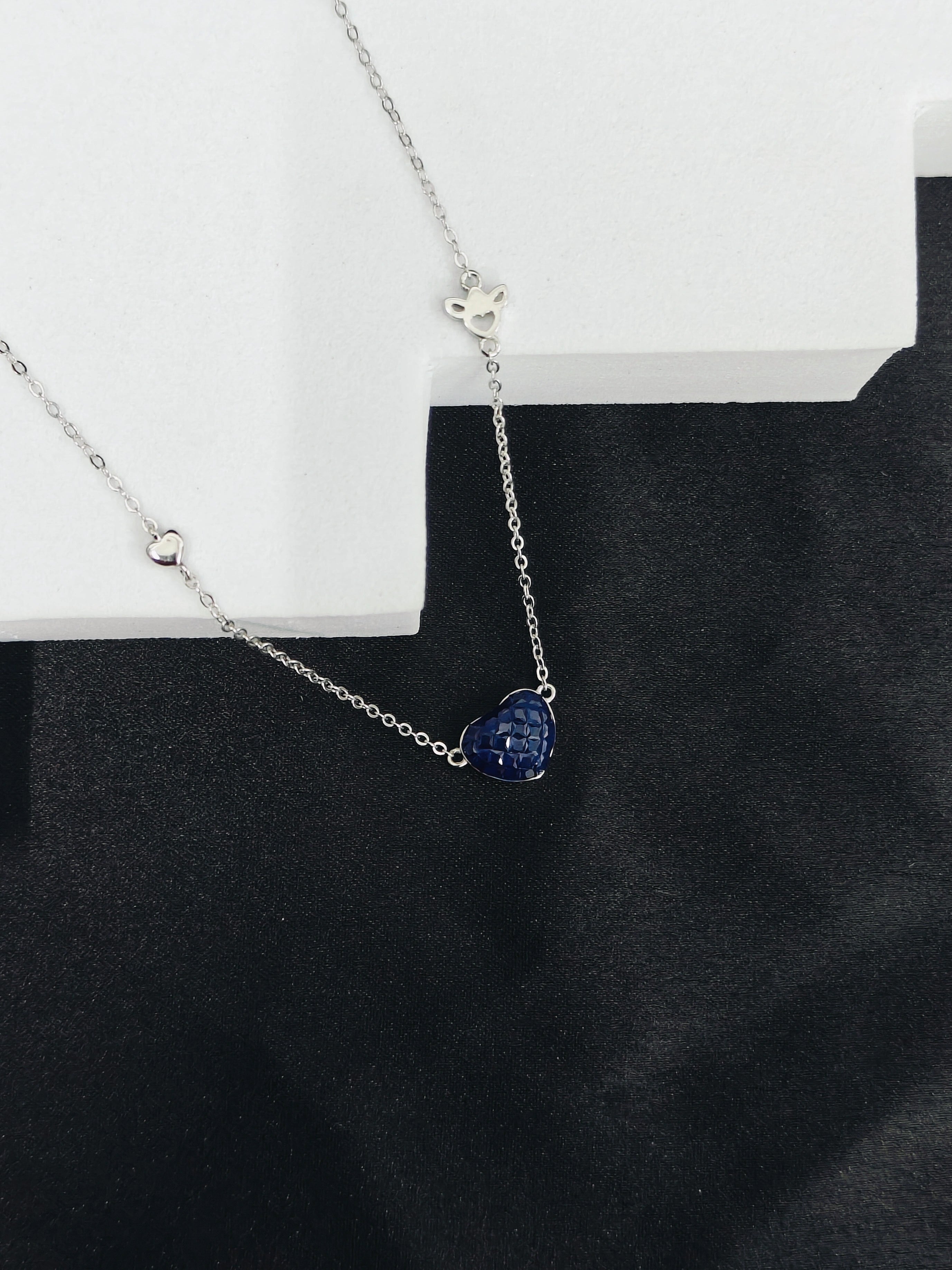 Necklace with a blue heart-shaped pendant on a black surface