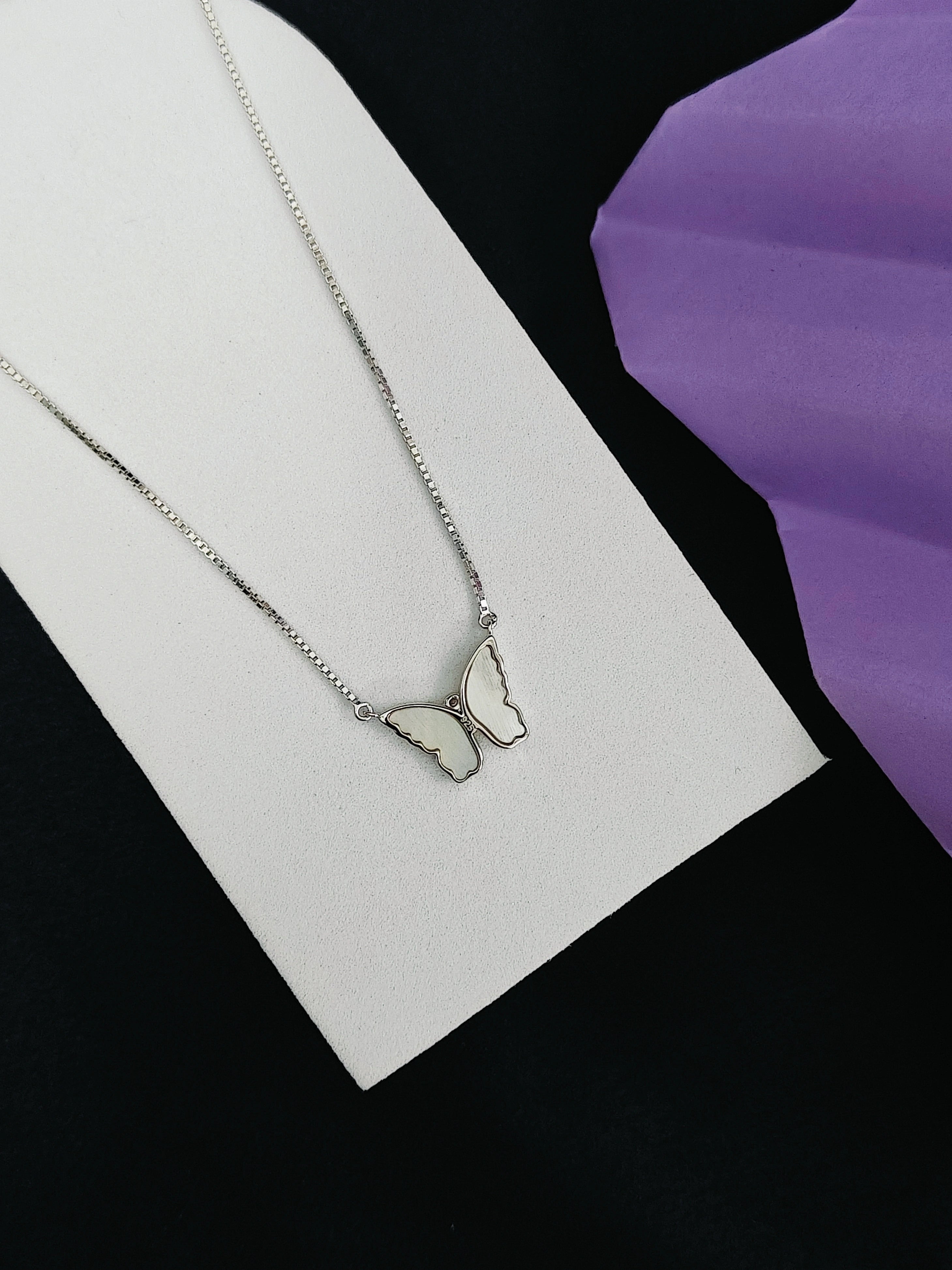 Butterfly necklace on a white card with a purple background