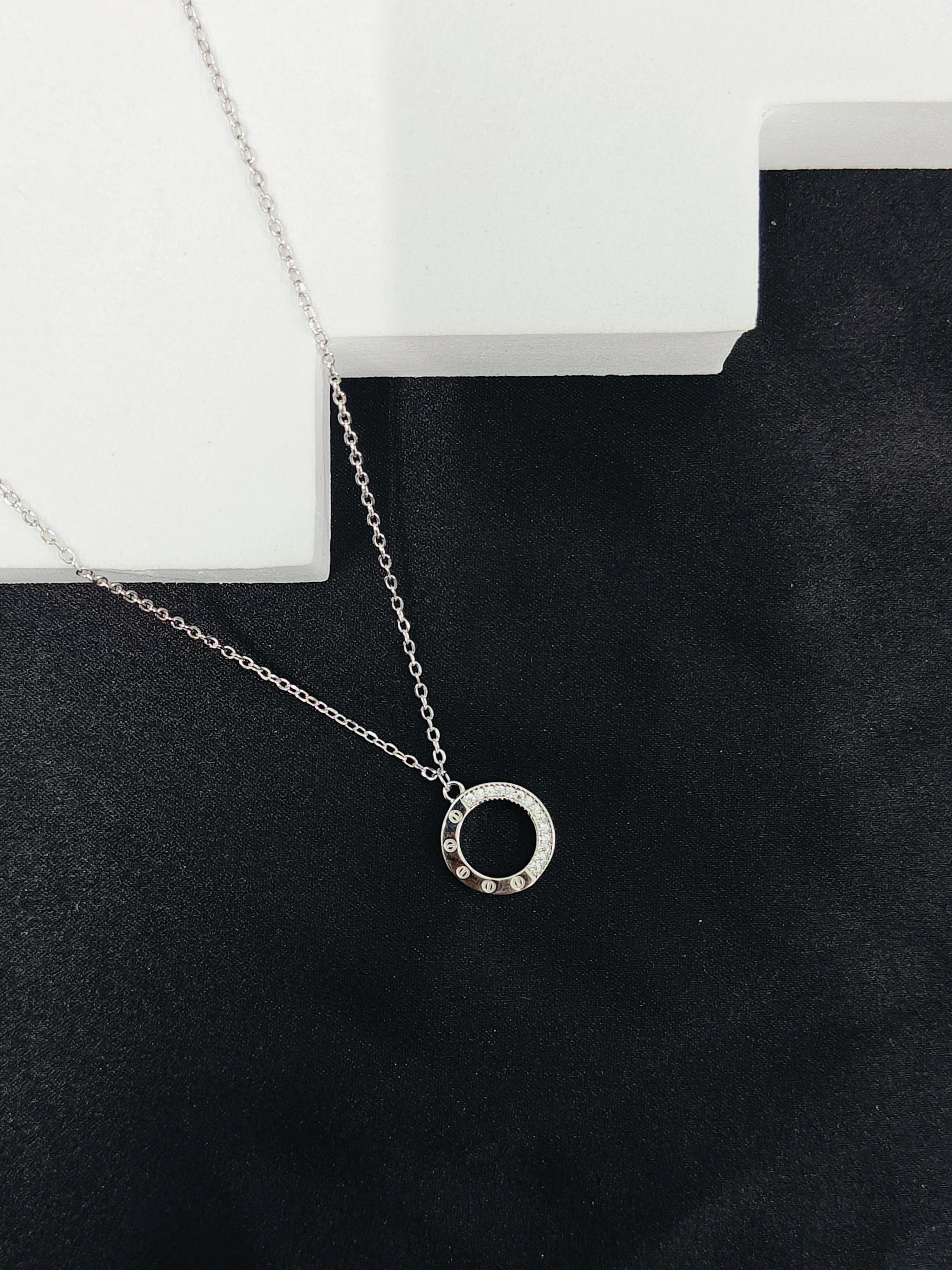 Silver necklace with a circular pendant on a black surface