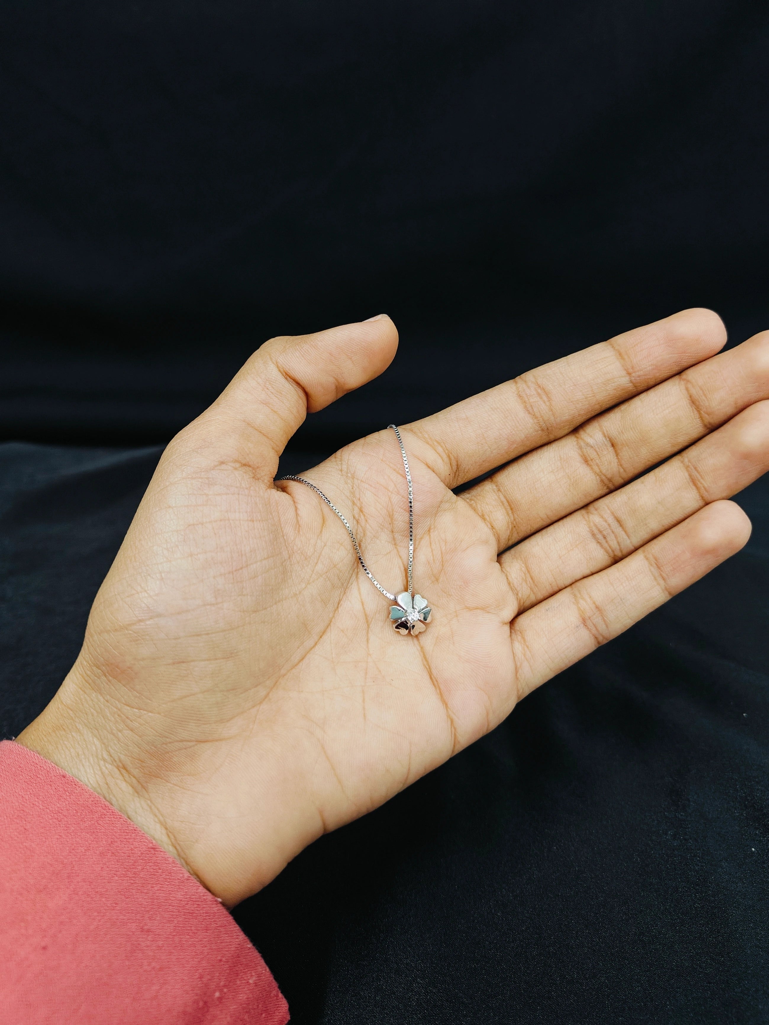 Hand holding a delicate necklace with a black background