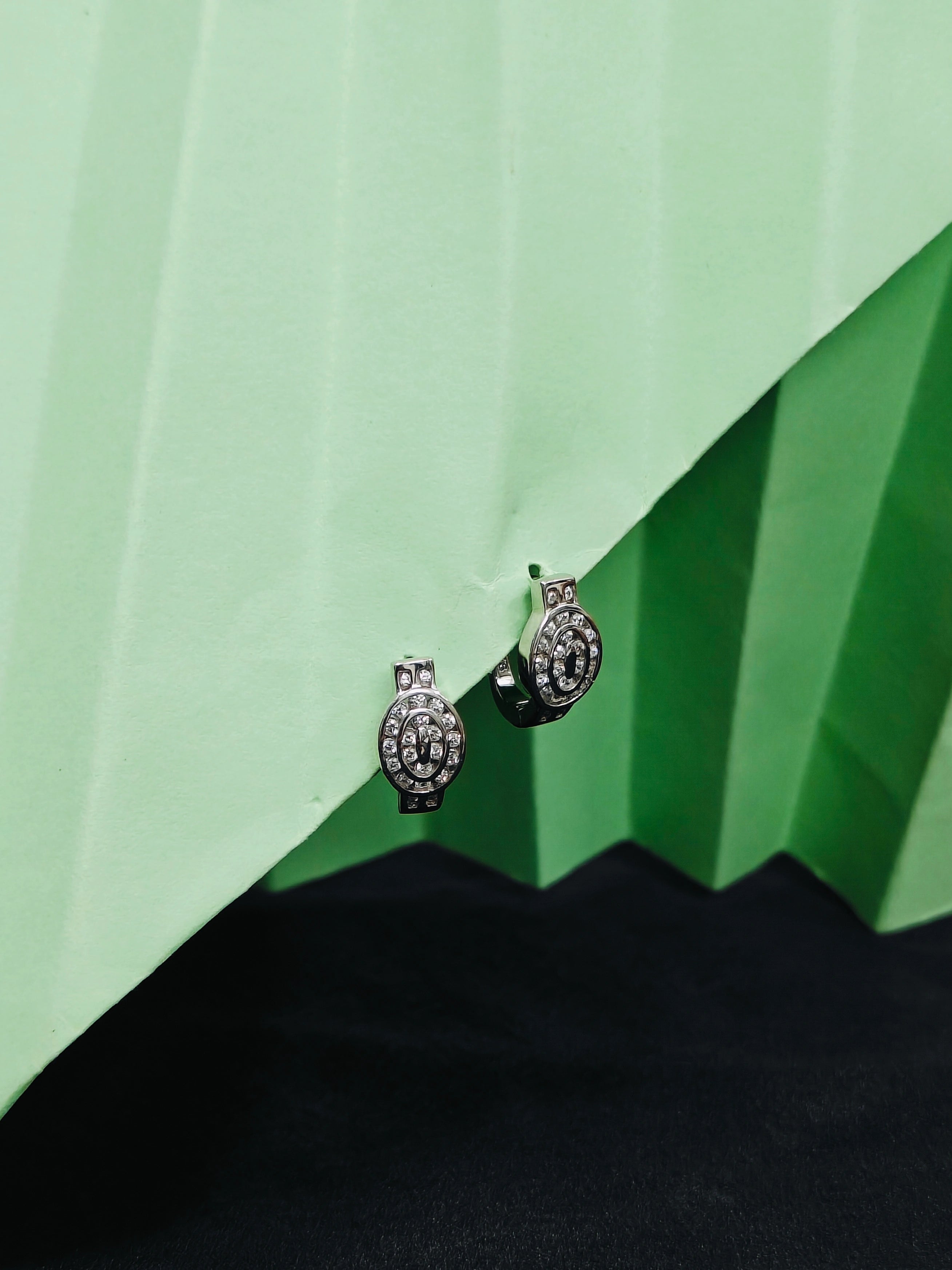 Pair of silver earrings with gemstones on a green and black background