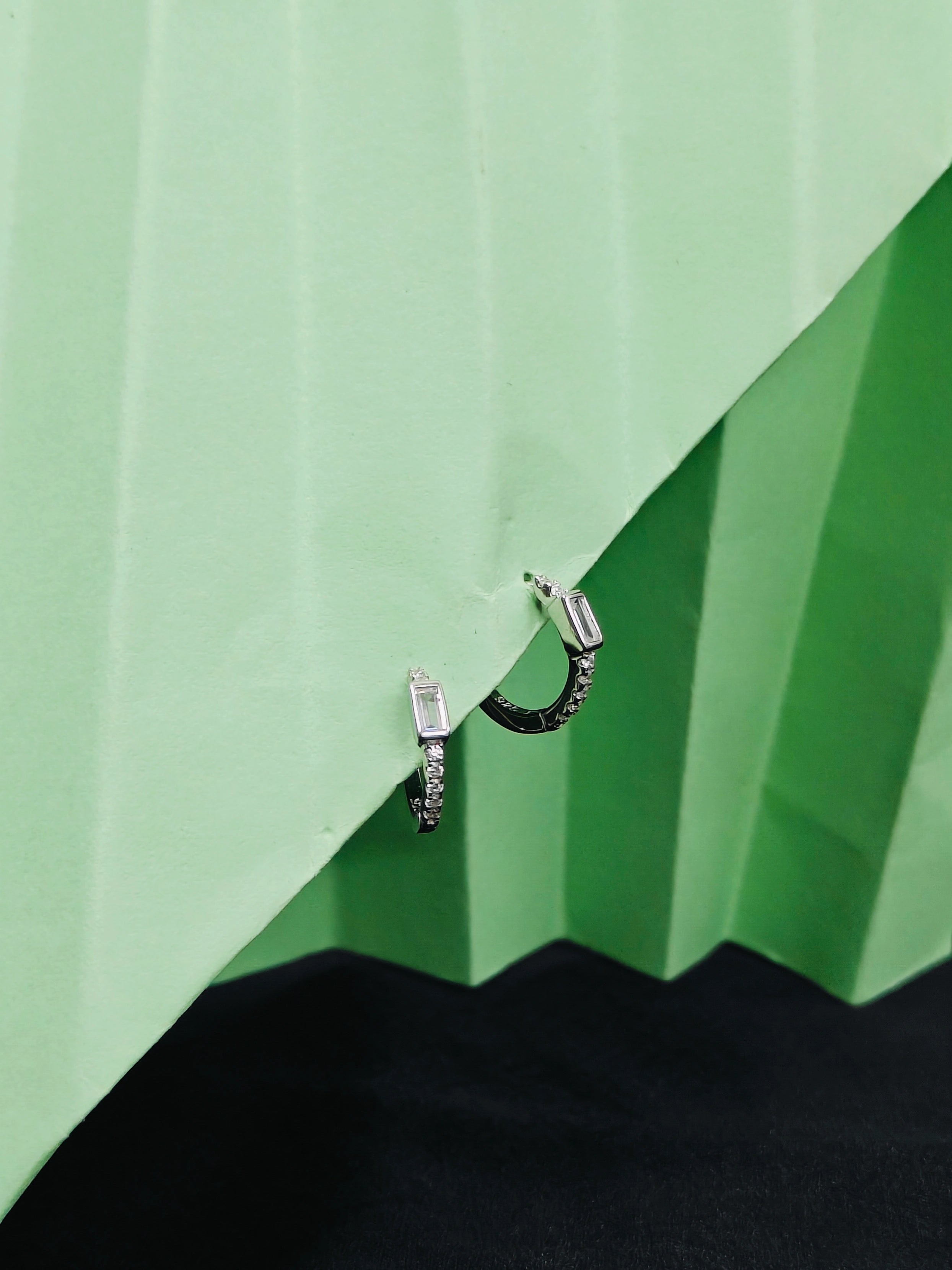 Pair of hoop earrings on a green and black geometric background