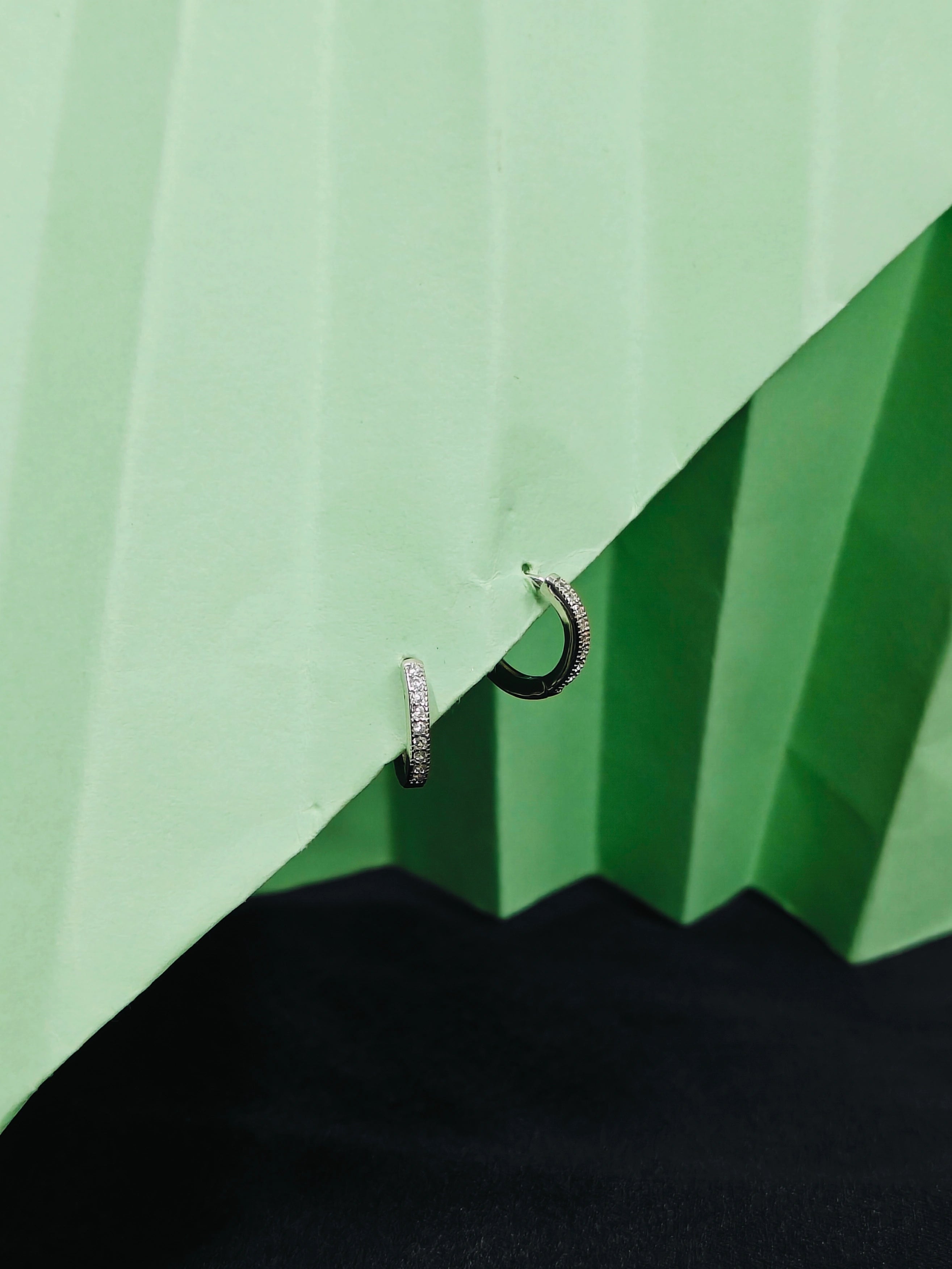 Two hoop earrings on a green and black geometric background