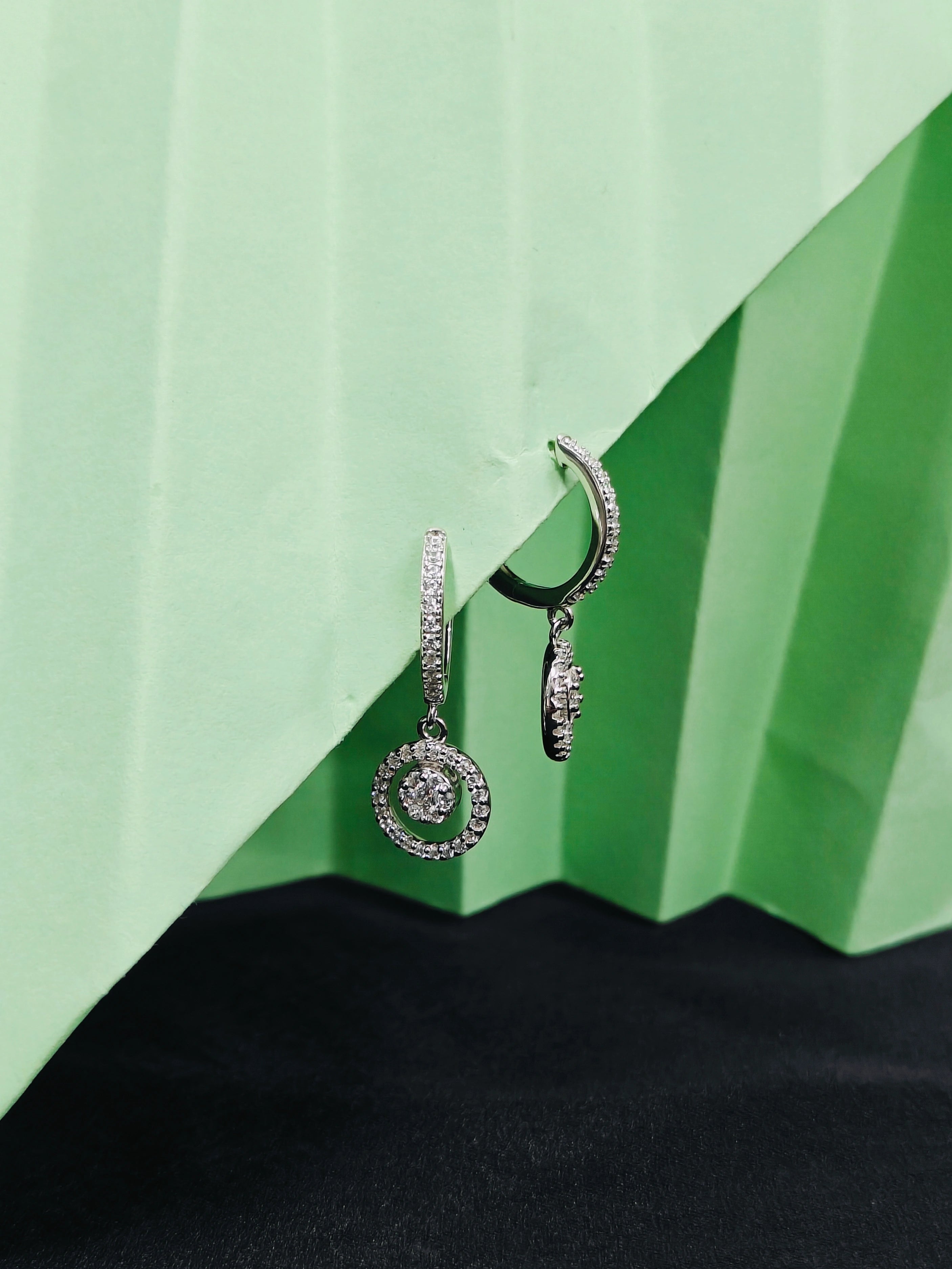 Pair of silver hoop earrings on a green geometric background