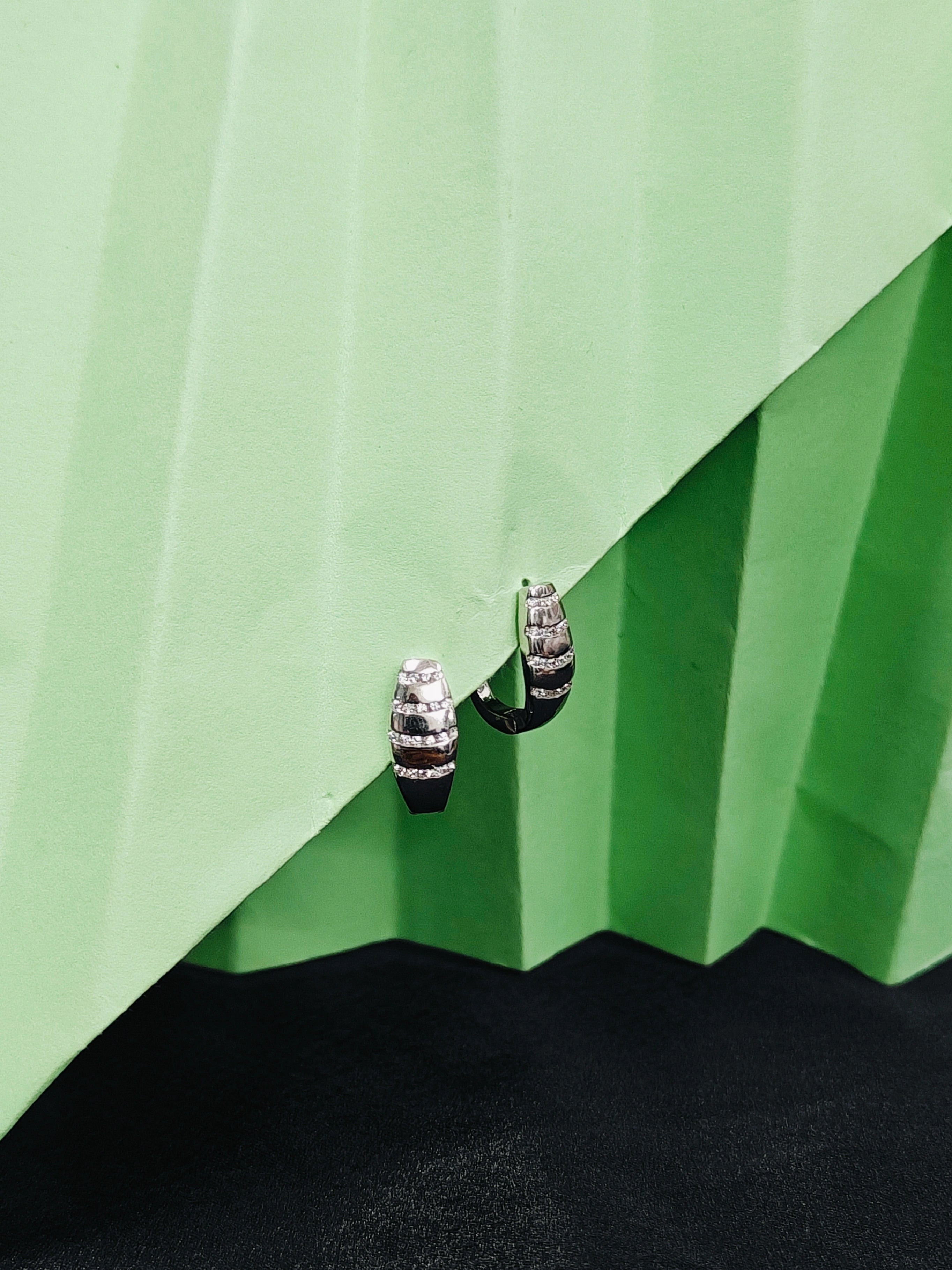 Silver earrings on a green textured surface