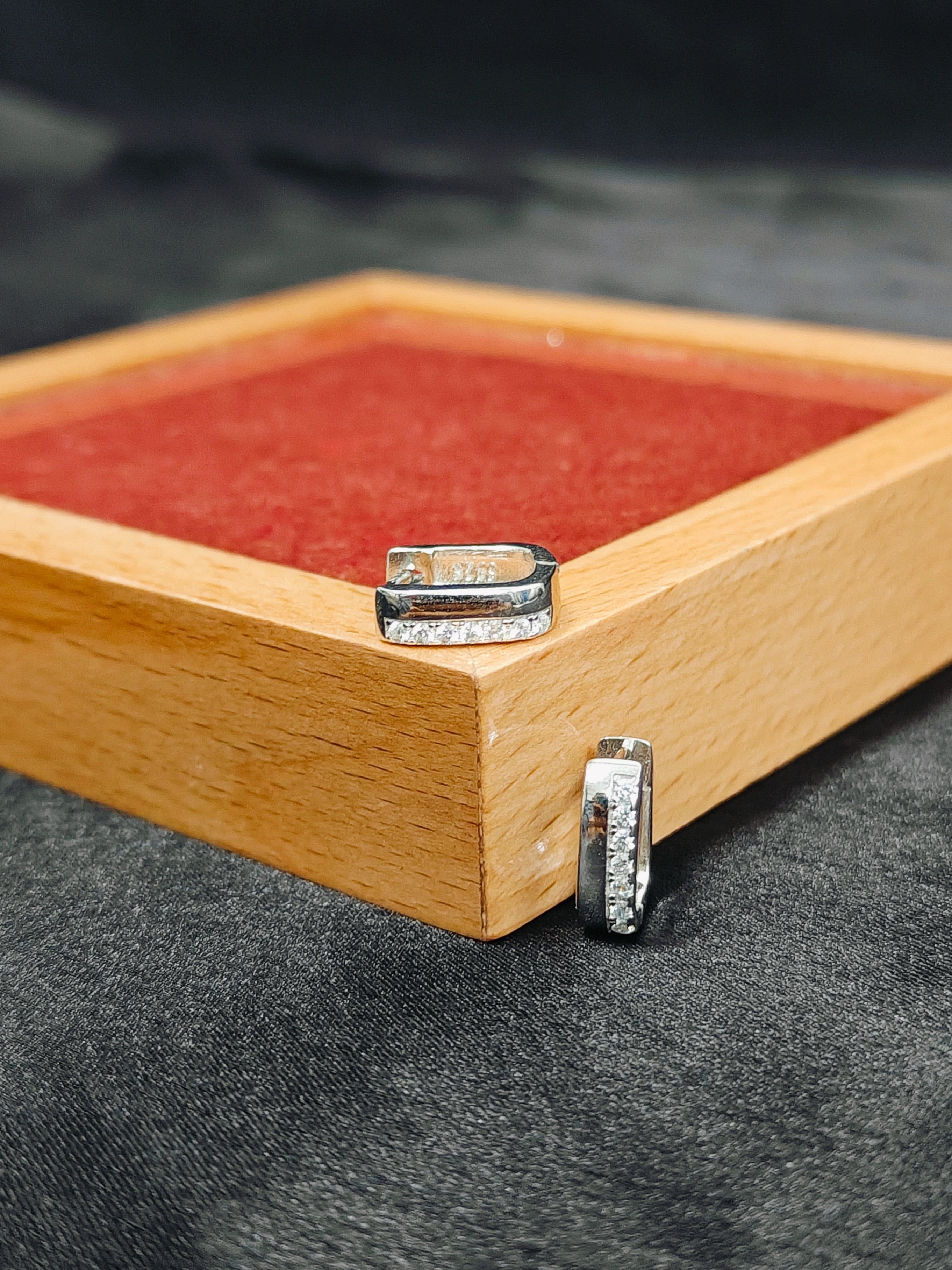 Silver rings on a wooden box with a red interior