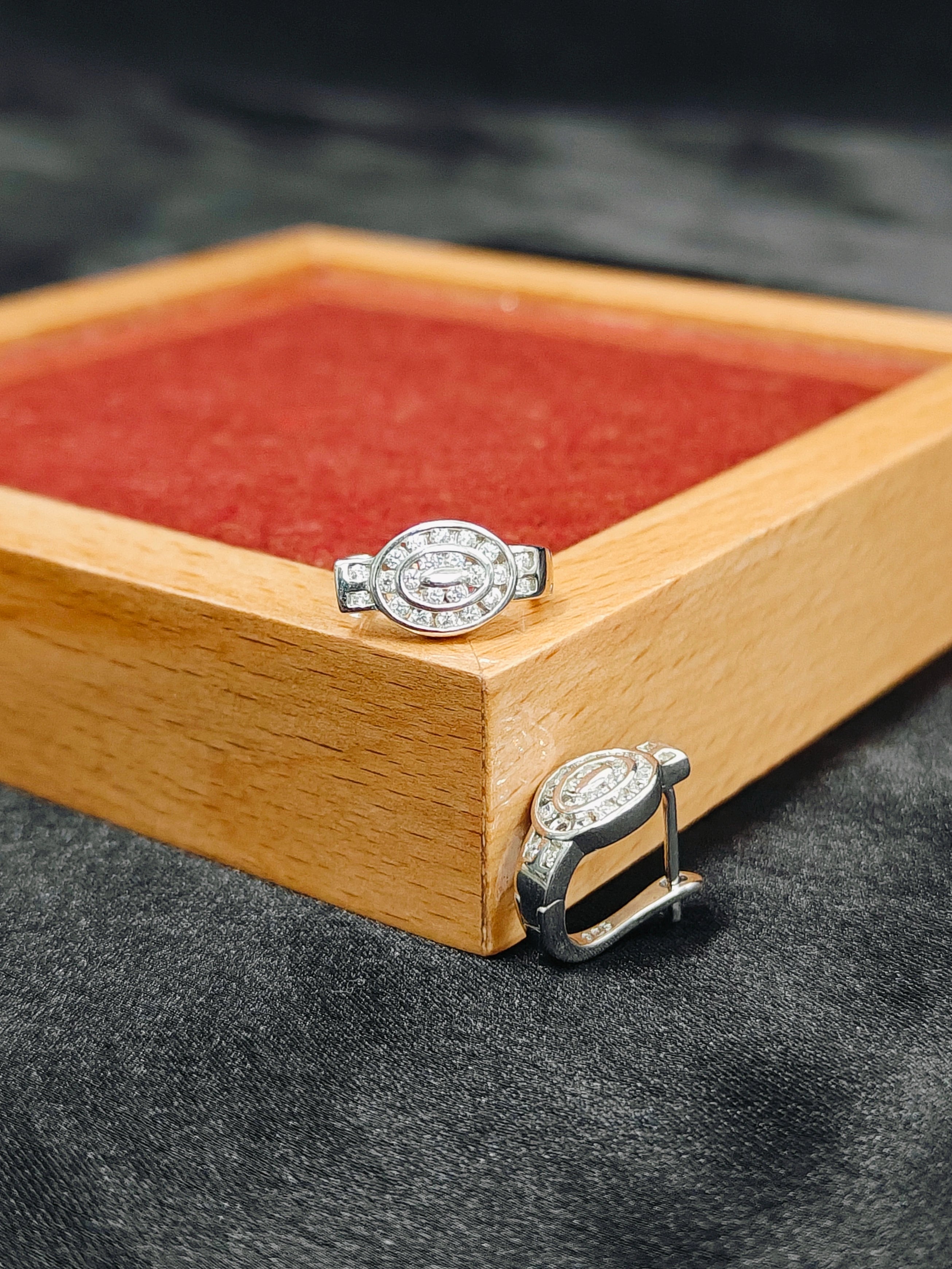 Silver ring with gemstones on a wooden stand against a dark background