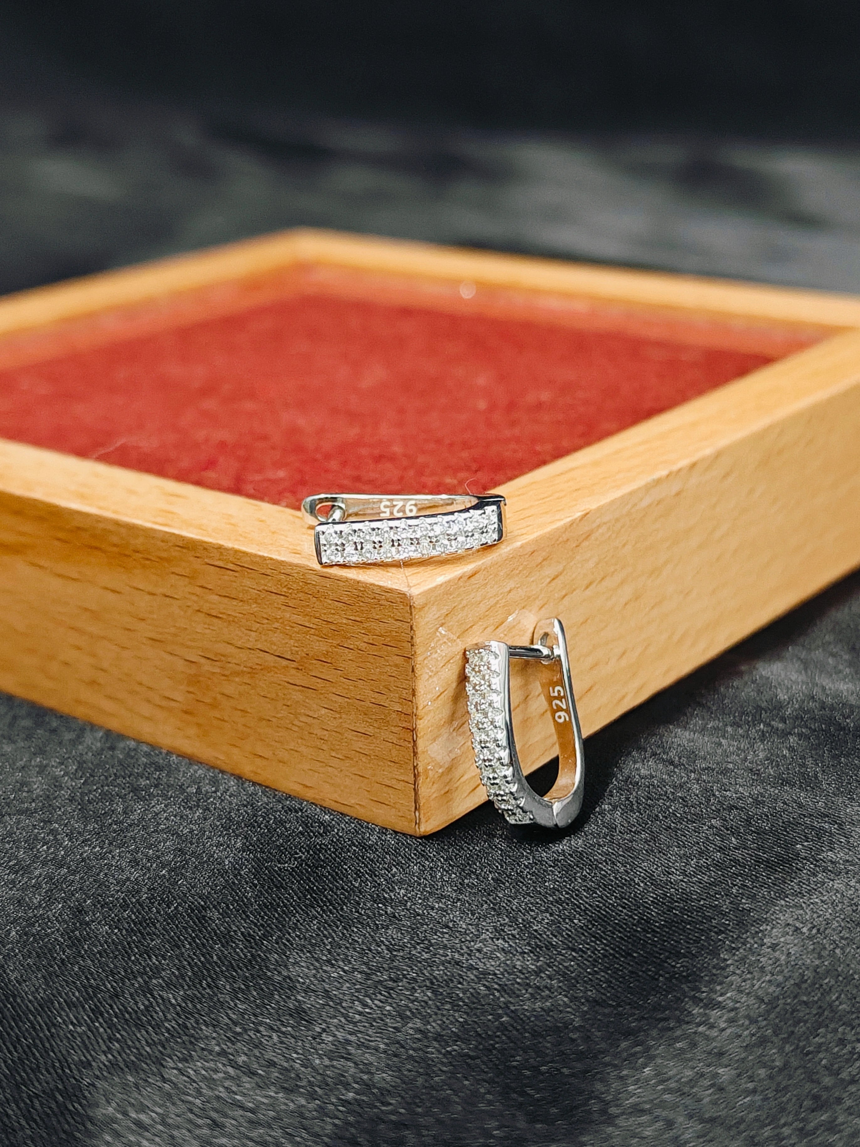 Pair of silver hoop earrings on a wooden stand with a dark background