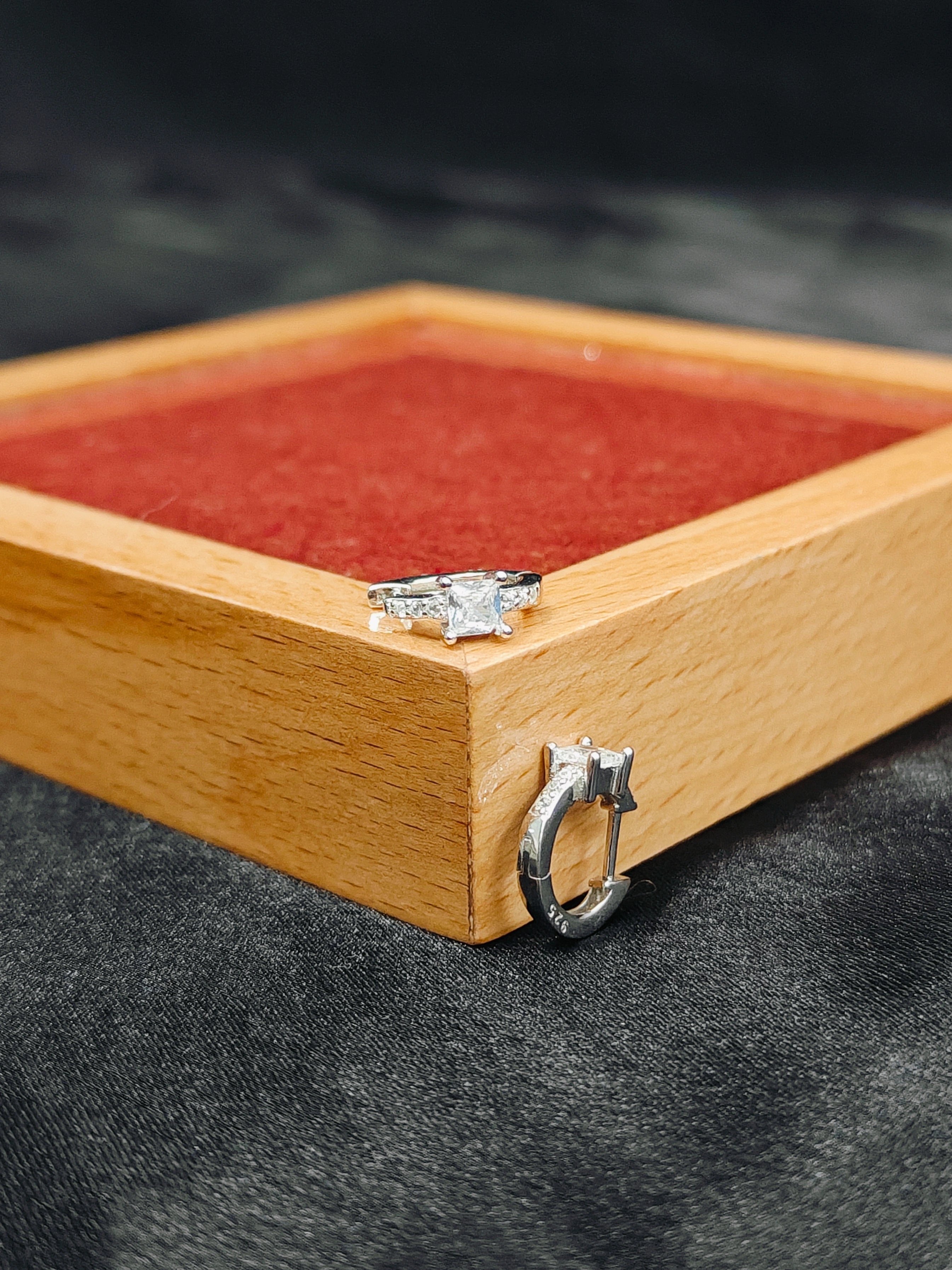 Silver ring on a wooden jewelry box with red interior