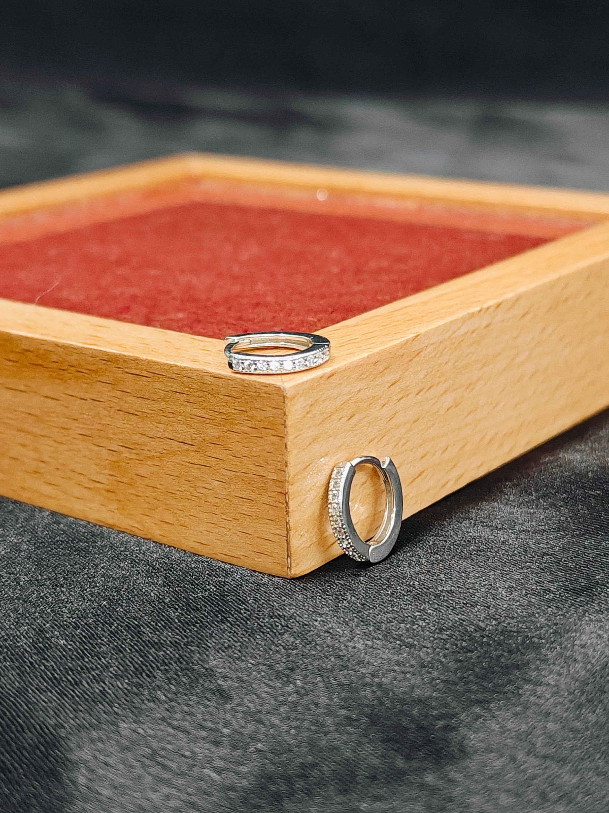 Two silver rings on a wooden box with a red interior.