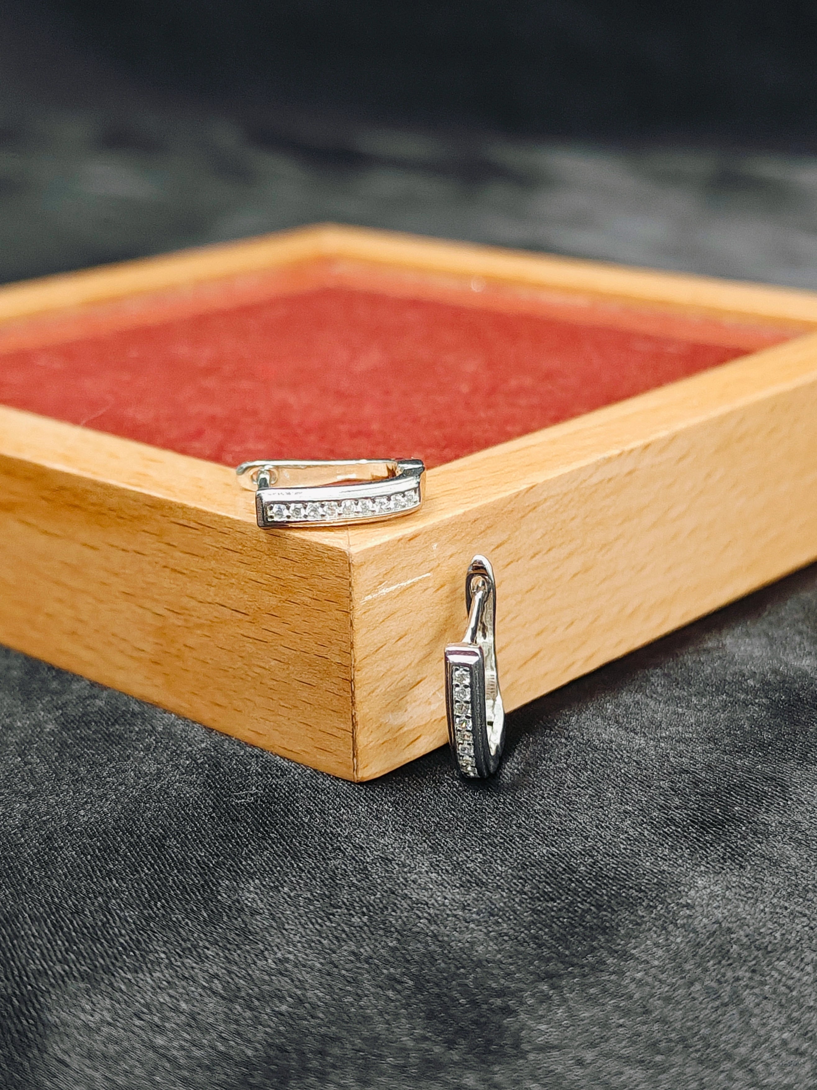 Two silver rings on a wooden stand with a dark background