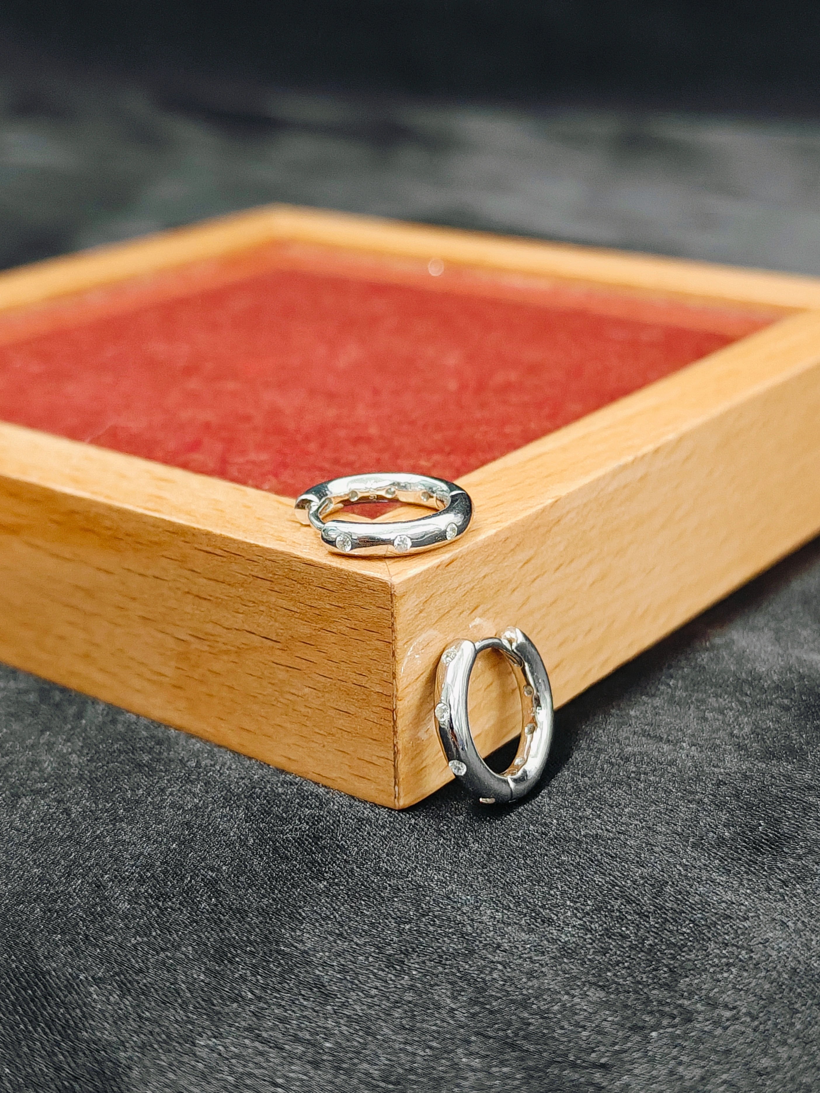 Two silver rings on a wooden tray with red fabric