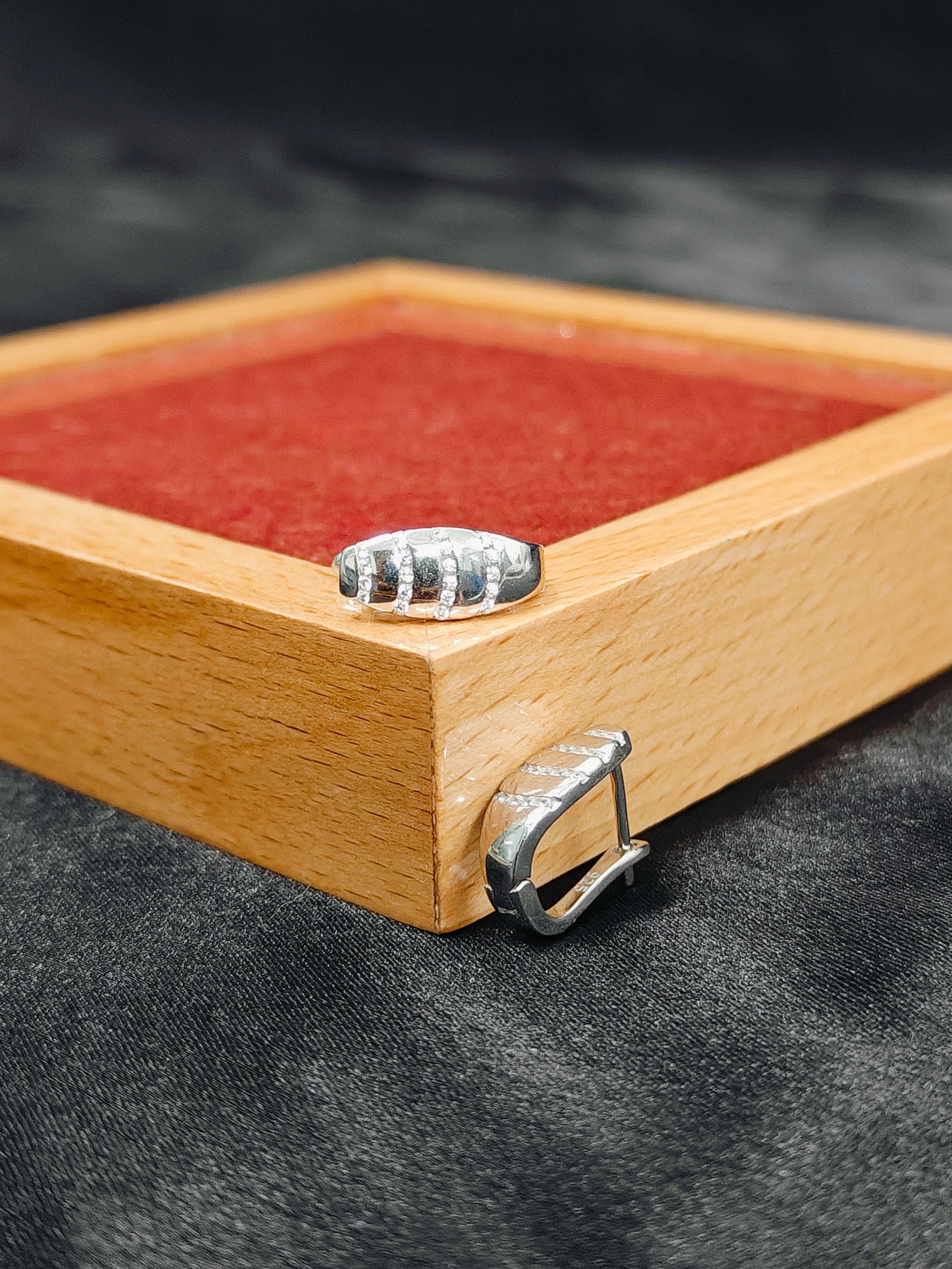 Wooden jewelry box with a red interior on a dark fabric background