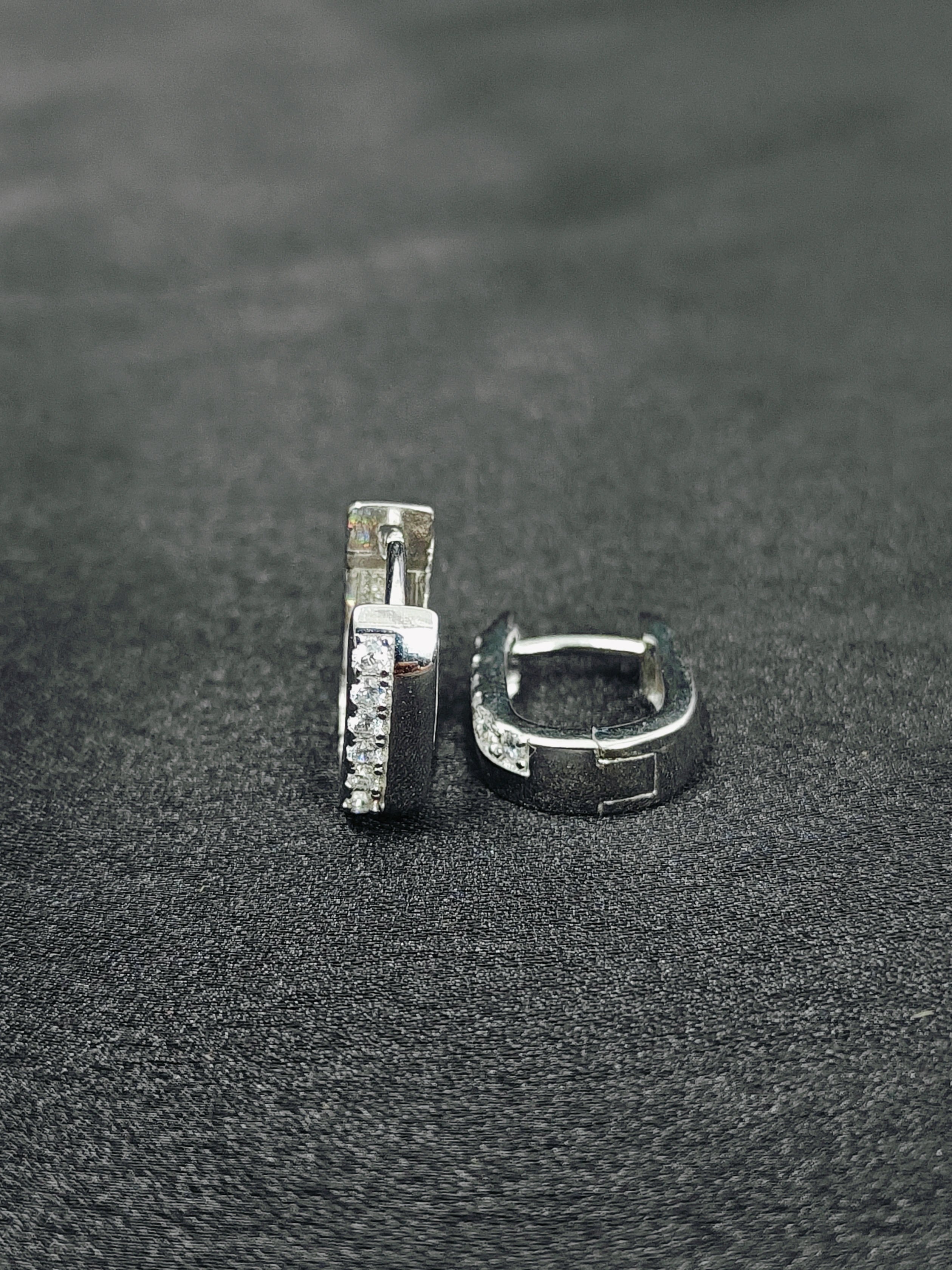 Pair of silver hoop earrings on a dark textured surface