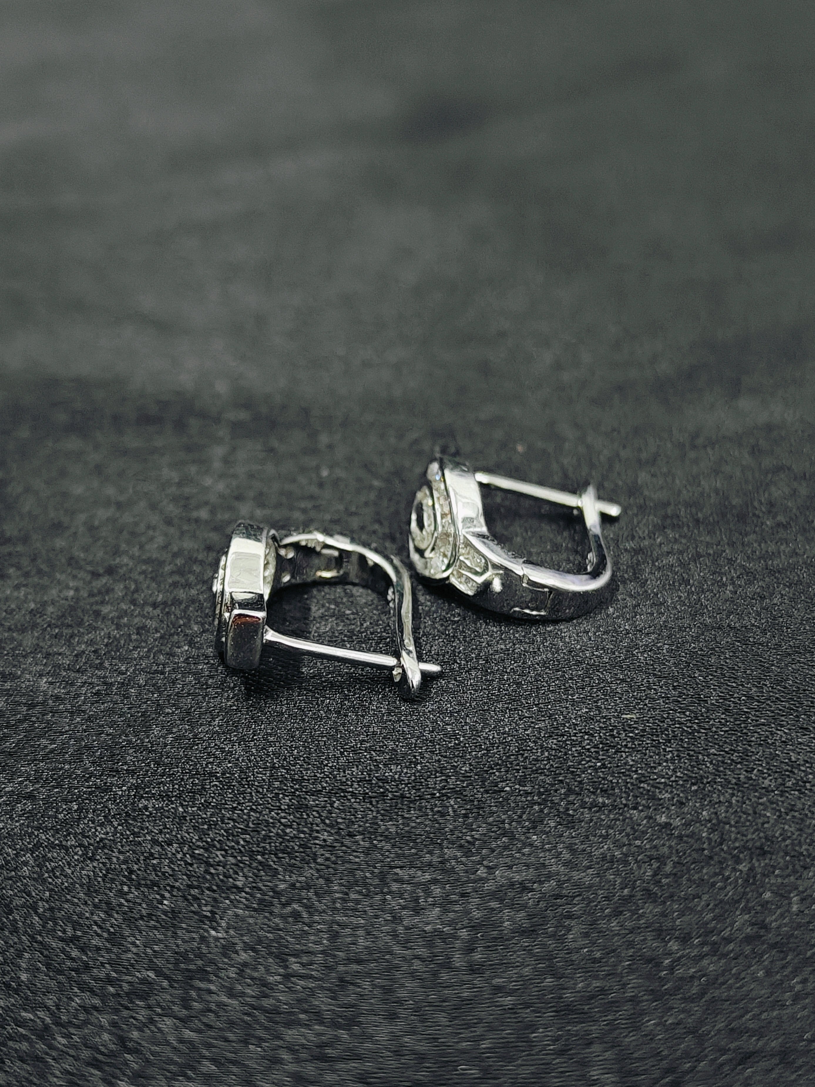 Pair of silver earrings on a black textured surface