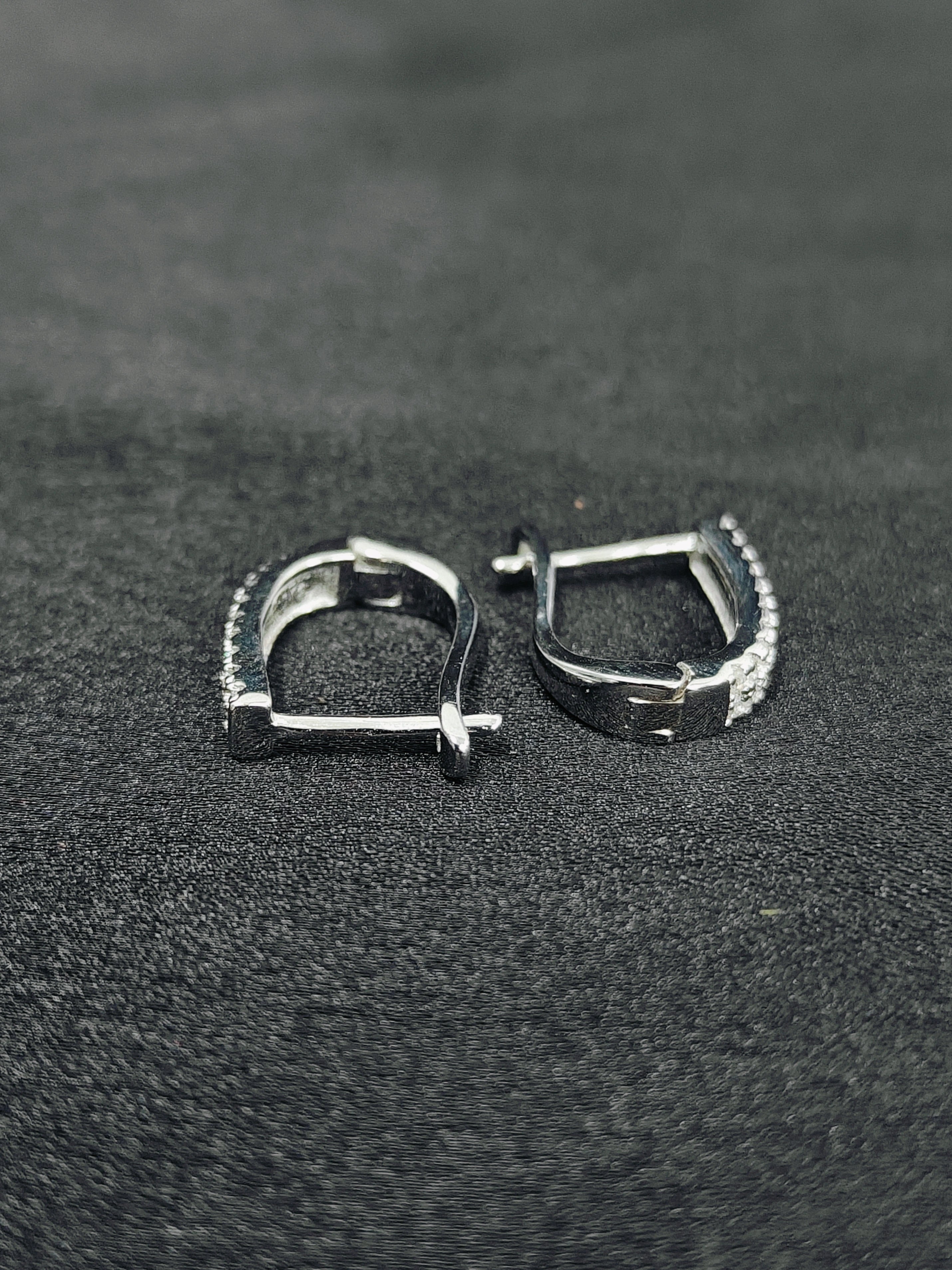 Pair of silver hoop earrings on a dark textured surface