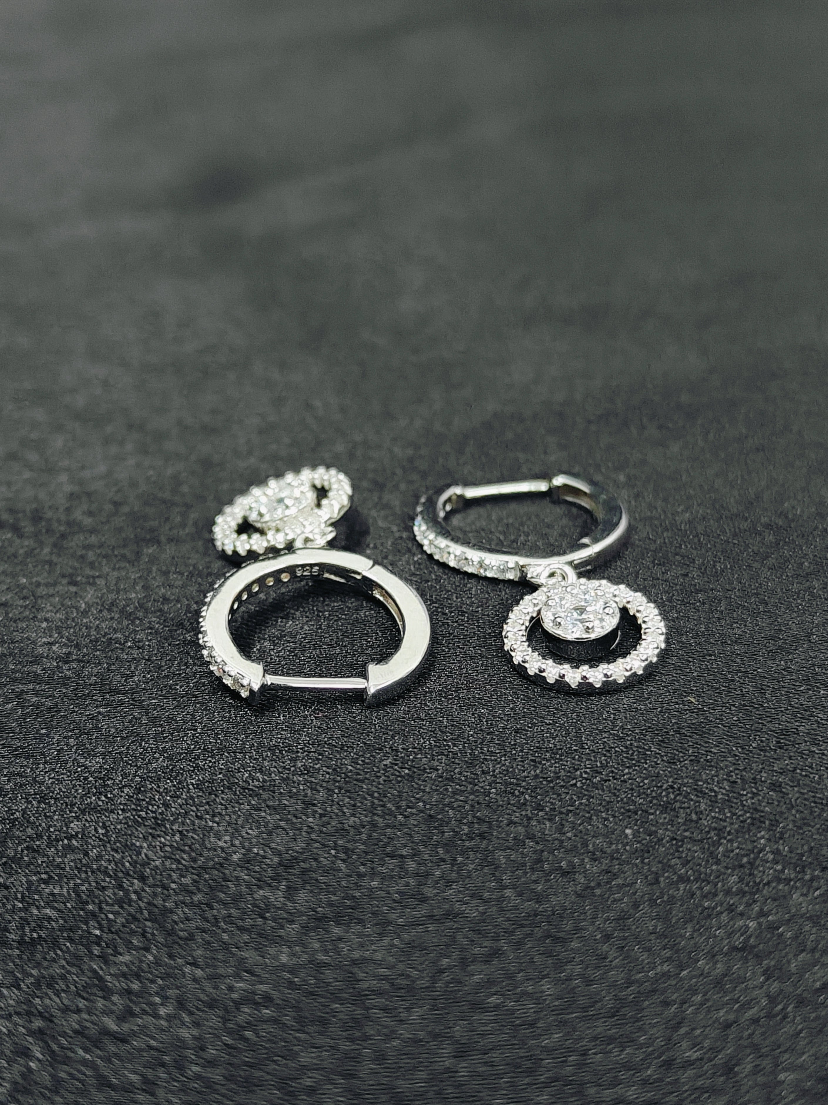 Pair of silver hoop earrings on a dark textured surface